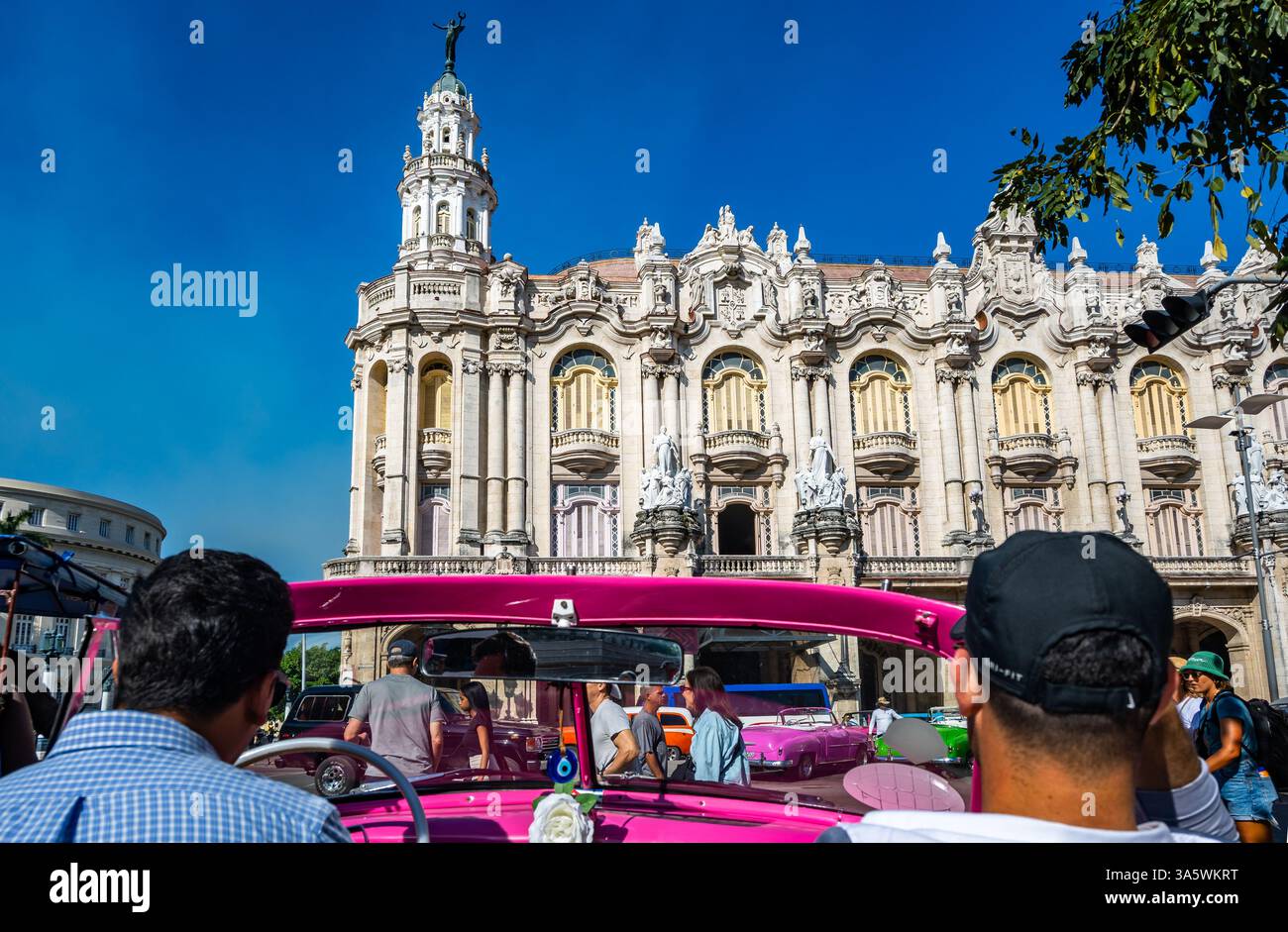 Touristen im Oldtimer, die im Centro Havana, Kuba, durch das Grand Theater oder das Gran Teatro de La Habana fahren. Stockfoto