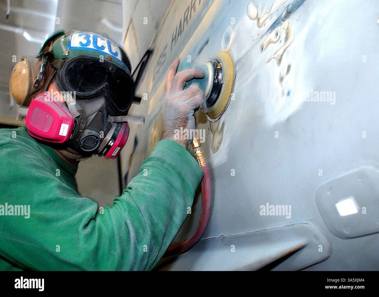 30. Juni 2004; Mittelmeer; Luftfahrzeugmaschinist's Mate 3rd Class Ross Christie, der der Jagdgeschwader drei zwei (VF-32) „Schwertkämpfer“ zugeordnet ist, entfernt alte Farbe von einer F/A-18 Hornet in der Hangar-Bucht an Bord der USS Harry S. Truman. Truman ist einer von sieben Flugzeugträgern, die an Summer Pulse 2004 teilnehmen. Summer Pulse 2004 ist der gleichzeitige Einsatz von sieben Flugzeugträger-Streikgruppen (CSGs), die die Fähigkeit der Navy demonstrieren, glaubwürdige Kampfkraft auf der ganzen Welt in fünf Theatern mit anderen US-amerikanischen, alliierten und koalitionellen Streitkräften bereitzustellen. Summer Pulse ist der erste Einsatz der Navy Stockfoto