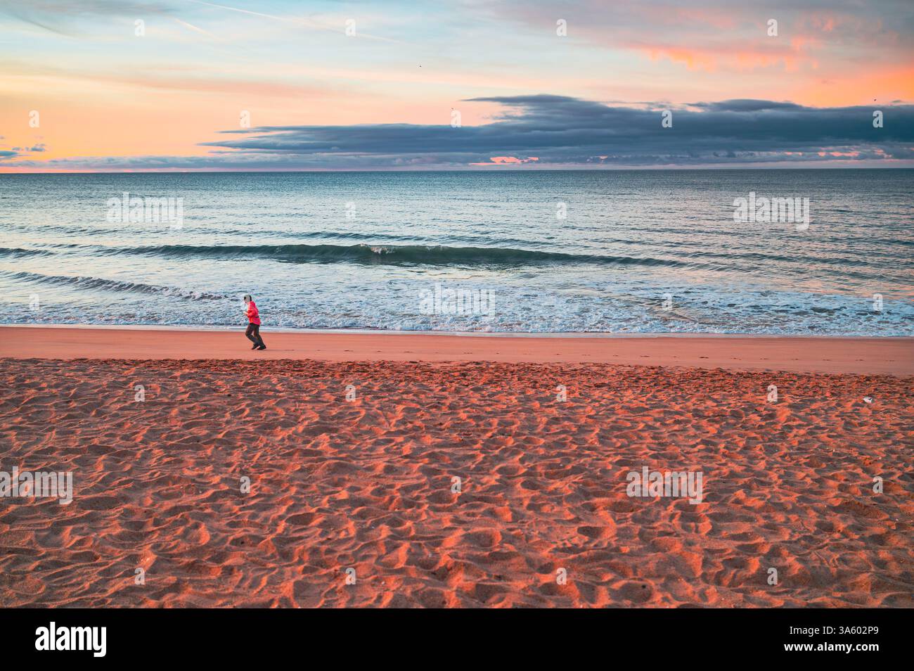 Läufer am violetten Morgenstrand. Aktiver Morgen in Pastellfarben Stockfoto