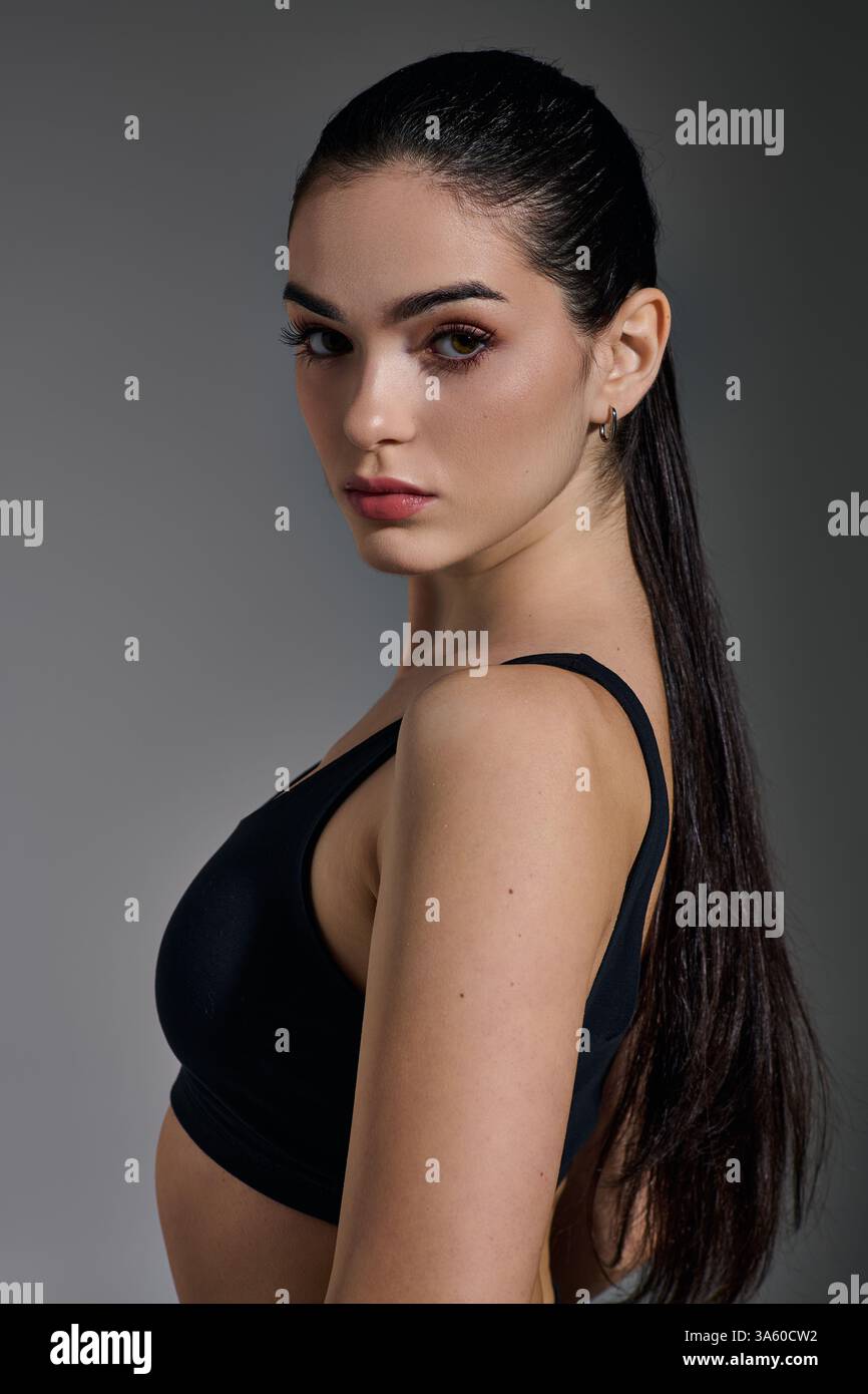 Die sportliche junge Frau posiert selbstbewusst und zeigt ihren sportlichen Körper mit einem fokussierten Look. Stockfoto