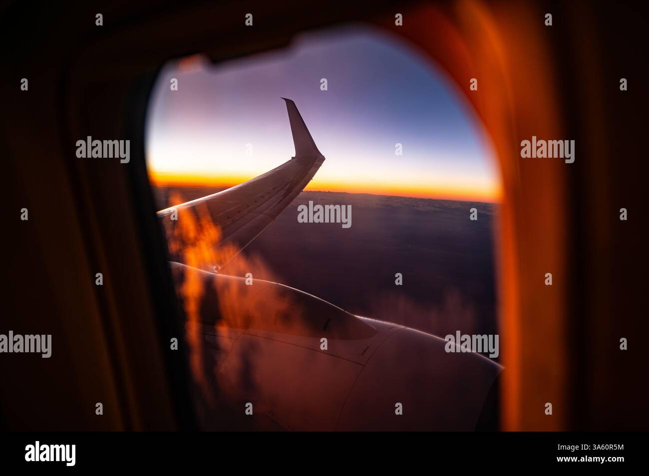 Sonnenuntergang von oben: Ein Flugzeugfenster als Tagesübergänge zur Nacht Stockfoto