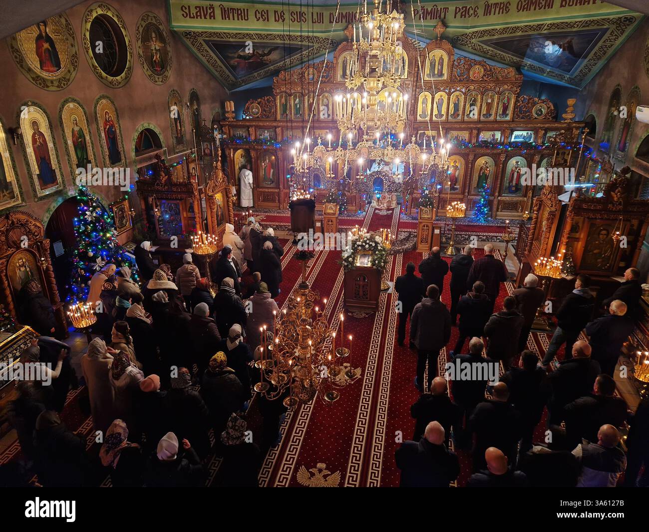 UNGHENI, MOLDAWIEN - 6. JANUAR 2025 Menschen beten in einer christlich-orthodoxen Kirche während des Gottesdienstes mit dem Priester, der Gebete vor der Kirche liest - Smartphone-aufgenommenes Stockfoto