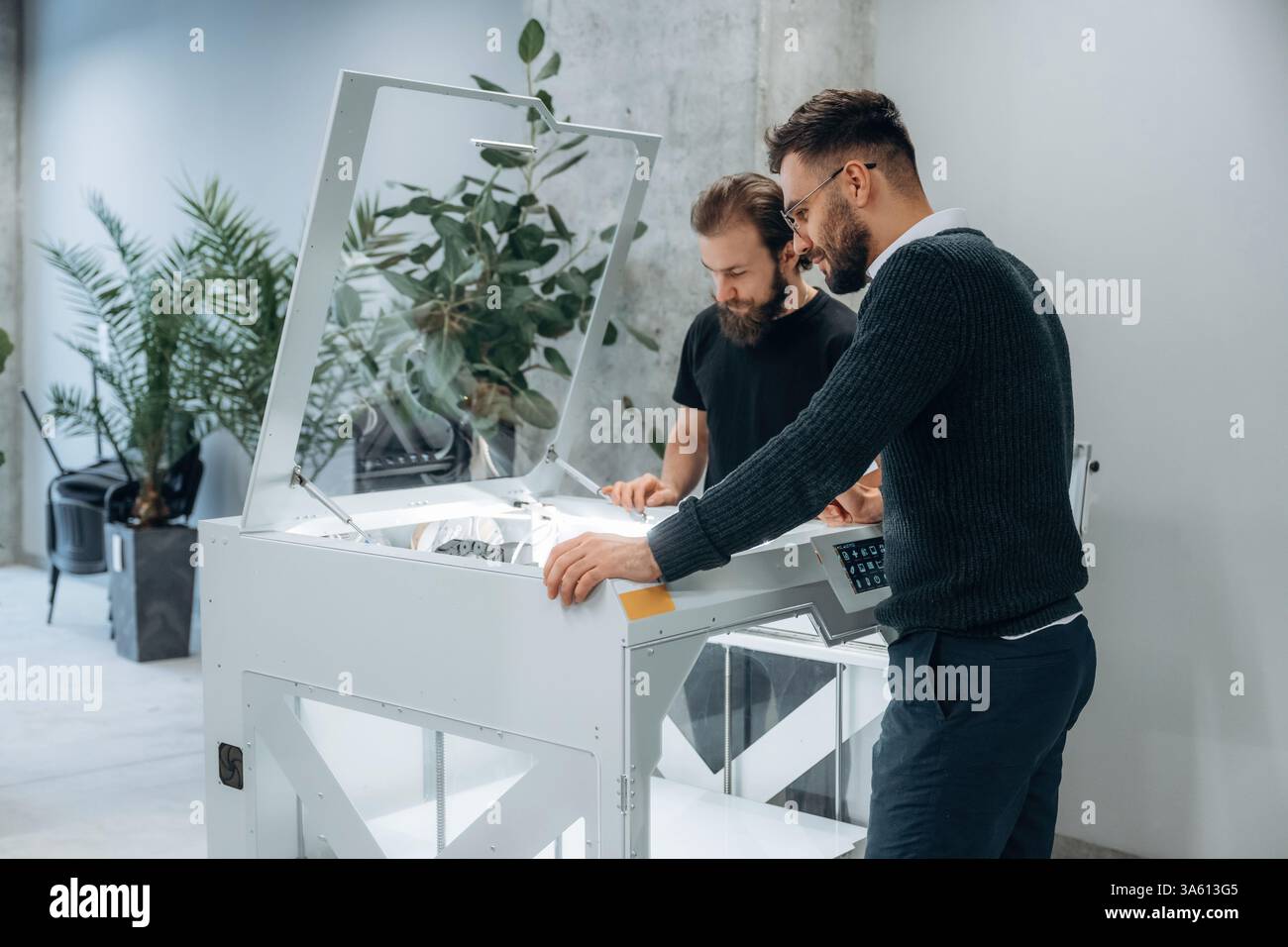 Zwei Männer stehen und arbeiten am 3D-Drucker. Stockfoto