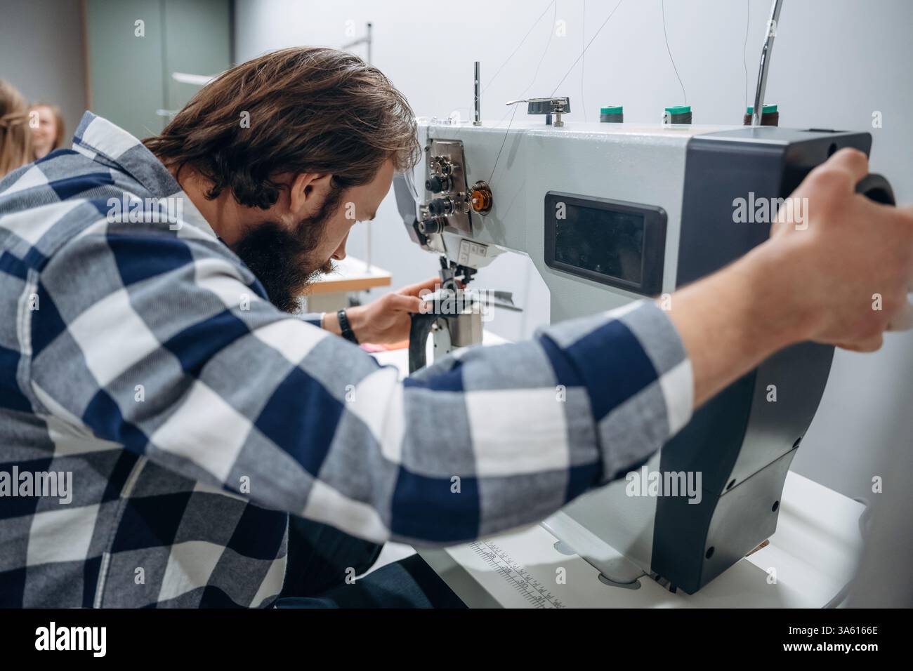 Die Menschen arbeiten an den Nähmaschinen in Innenräumen. Stockfoto
