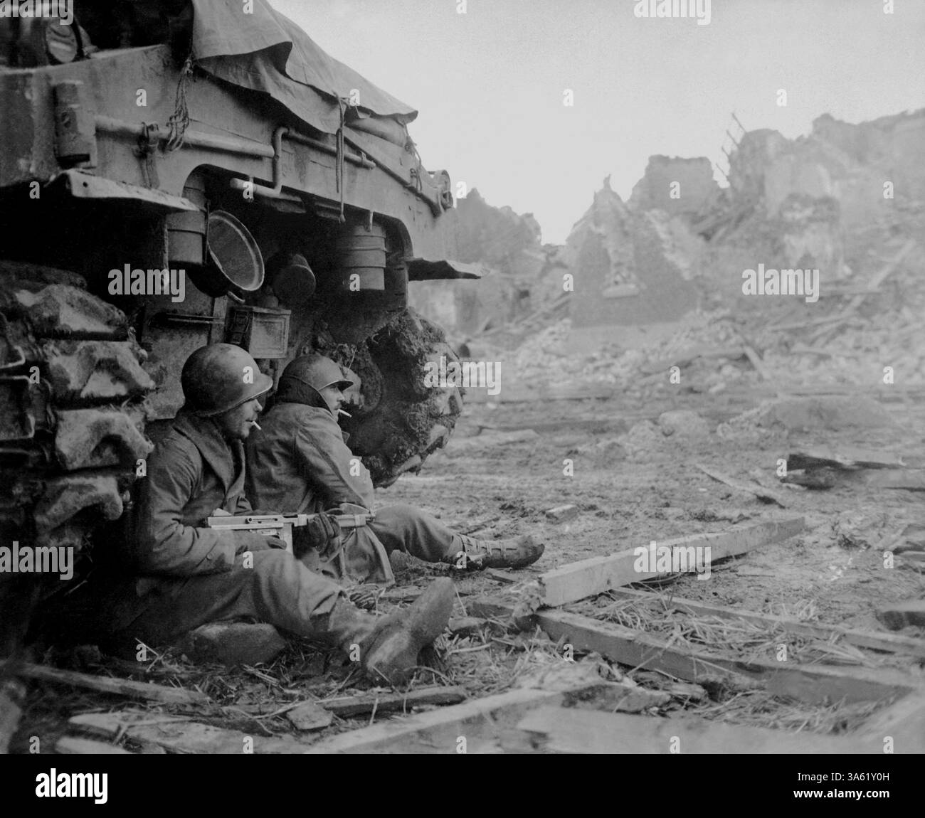 GEICH, DEUTSCHLAND - 11. Dezember 1944 - mit schreienden deutschen Granaten suchen amerikanische Infanteristen Zuflucht hinter einem Panzer. Im Hintergrund können s sein Stockfoto