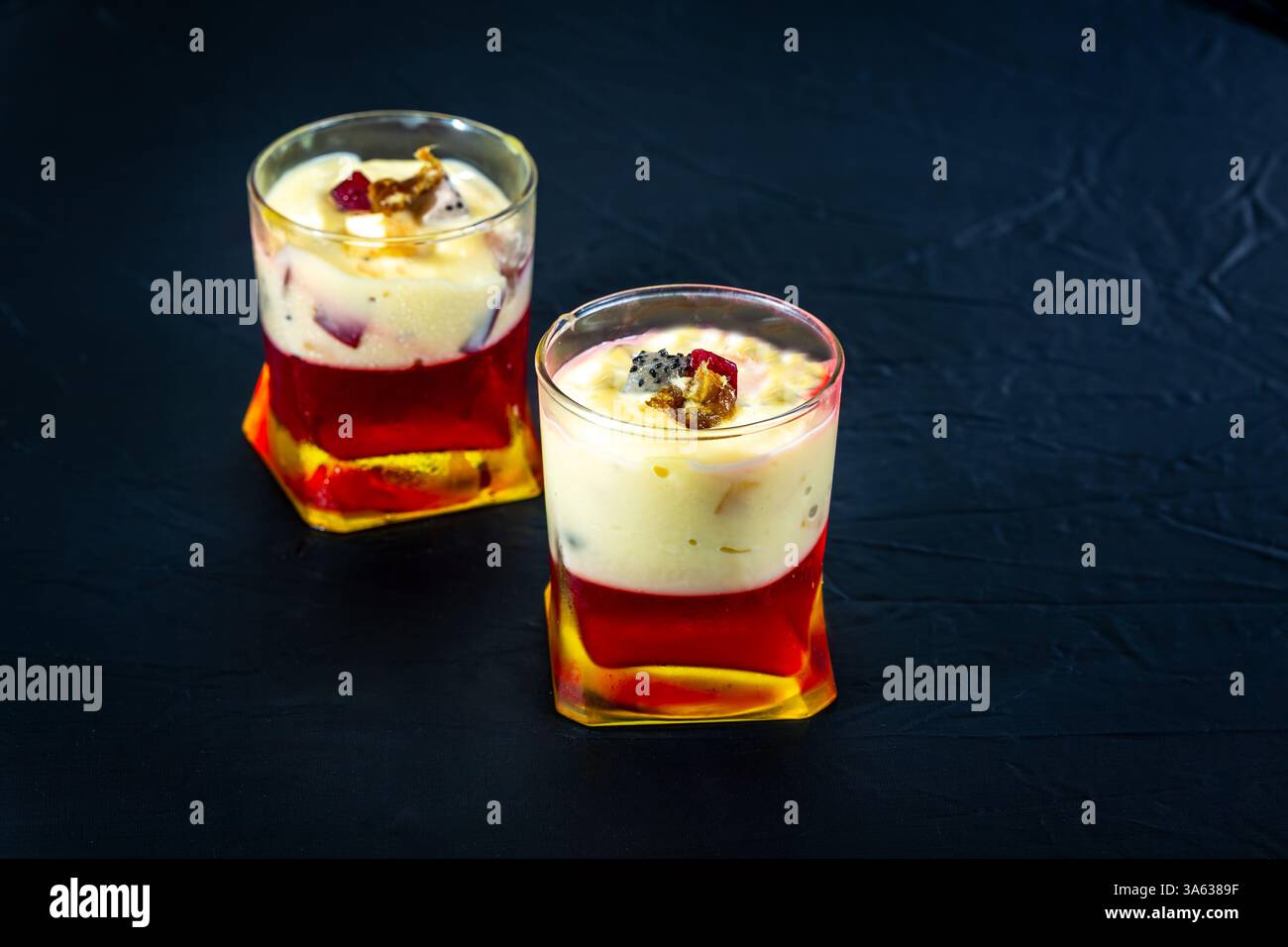 Süßes Dessert mit weißen milchigen, roten und rosa Schichten isoliert auf schwarzem Hintergrund. Blick auf frisch servierte Speisen in der Nähe Stockfoto Süßes Dessert mit weißen milchigen, roten und rosa Schichten isoliert auf schwarzem Hintergrund. Blick auf frisch servierte Speisen in der Nähe Stockfoto