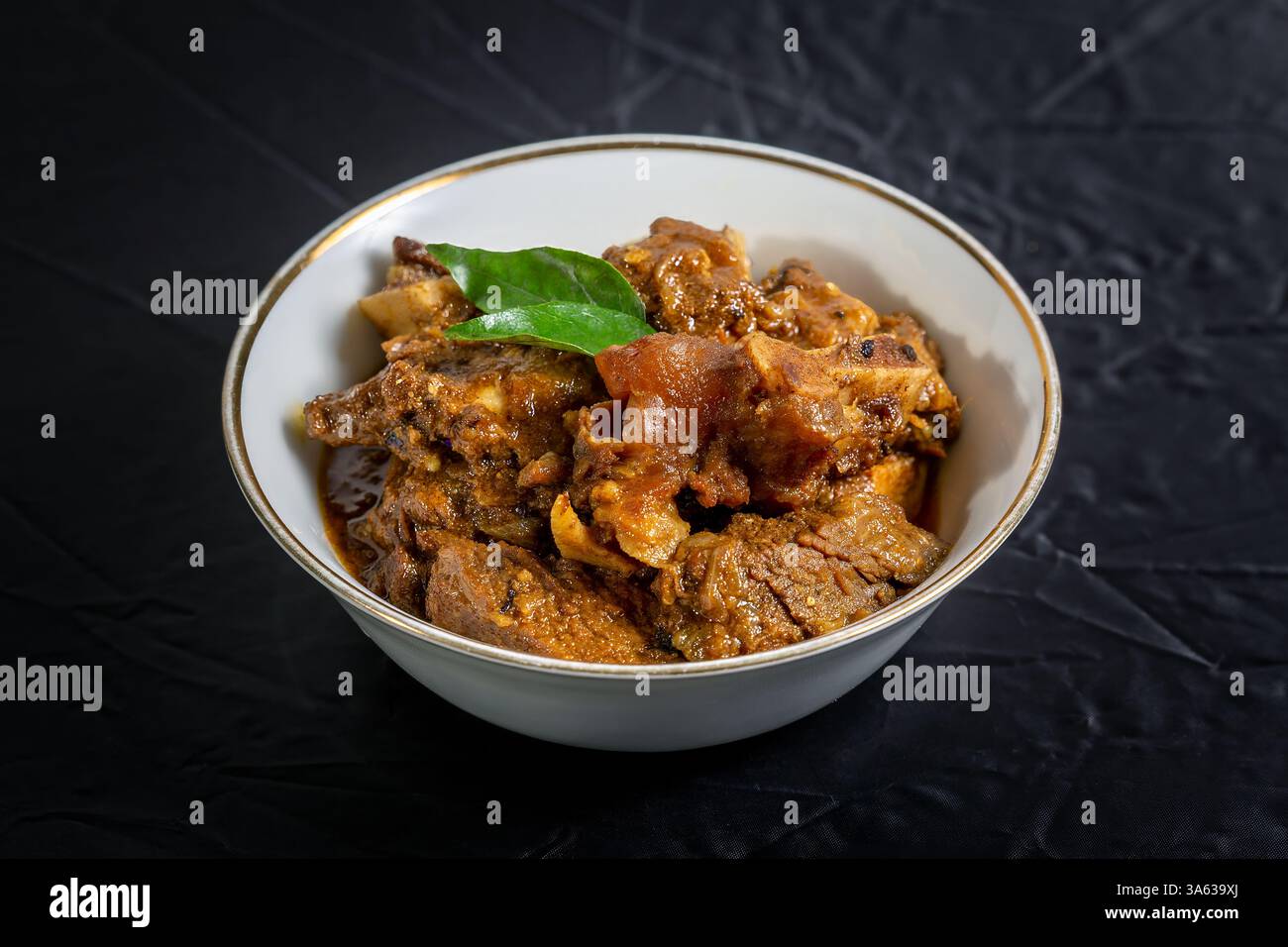 Rindfleisch Masala oder Braten, hausgemachtes Rezept nach Kerala-Art, garniert mit Curryblättern und in einer weißen Schüssel auf schwarzem Hintergrund serviert. Stockfoto Rindfleisch Masala oder Braten, hausgemachtes Rezept nach Kerala-Art, garniert mit Curryblättern und in einer weißen Schüssel auf schwarzem Hintergrund serviert. Stockfoto