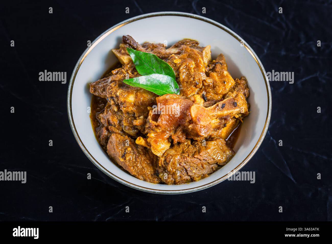 Rindfleisch Masala oder Braten, hausgemachtes Rezept nach Kerala-Art, garniert mit Curryblättern und in einer weißen Schüssel auf schwarzem Hintergrund serviert. Stockfoto Rindfleisch Masala oder Braten, hausgemachtes Rezept nach Kerala-Art, garniert mit Curryblättern und in einer weißen Schüssel auf schwarzem Hintergrund serviert. Stockfoto