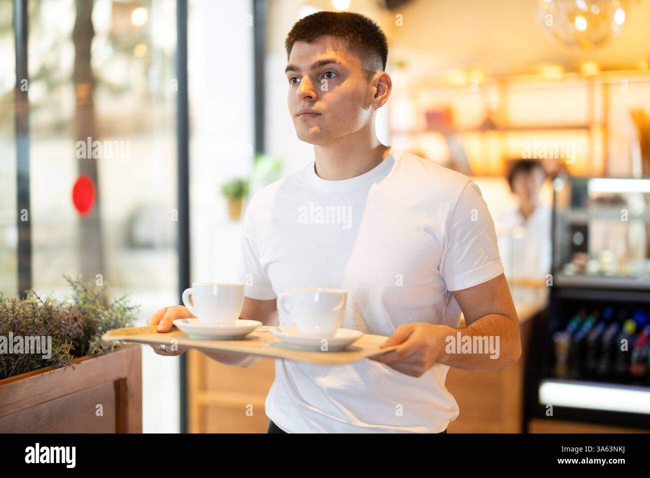 Ein Mann hält ein Tablett mit Kaffeetassen in der Hand Stockfoto