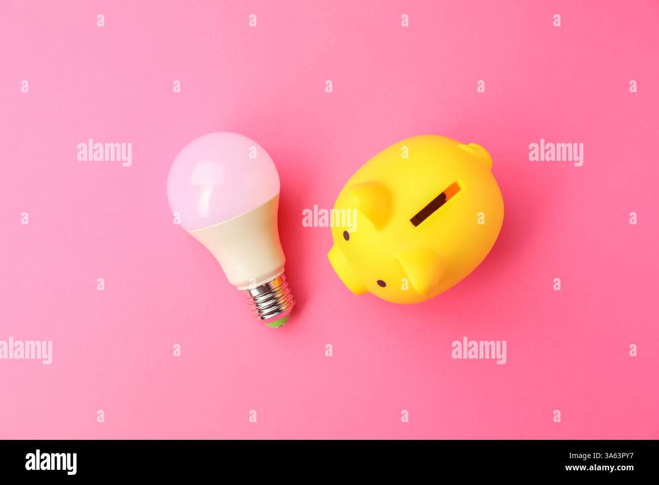 Schweinebank und Glühbirne auf rosafarbenem Hintergrund, flach. Energiesparkonzept Stockfoto