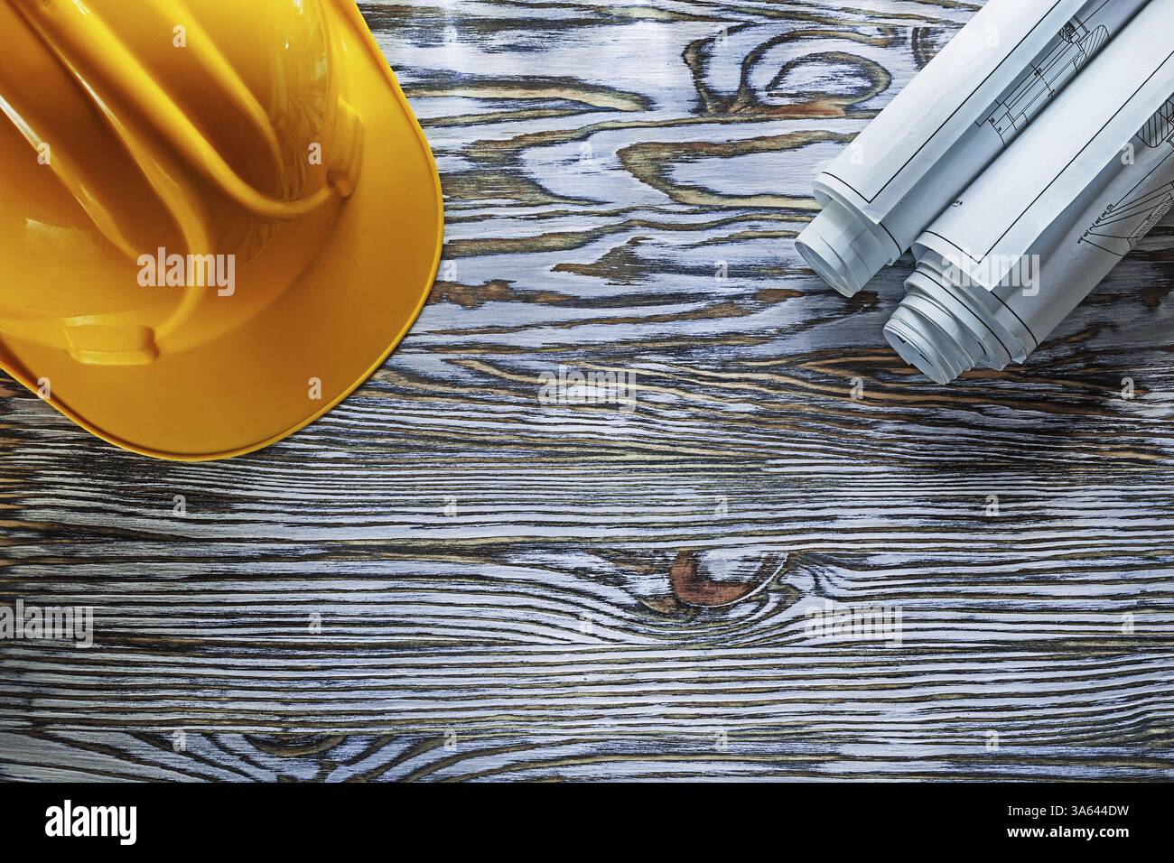 Gerollte Baupläne Schutzhelm auf Vintage Holzbrett Stockfoto