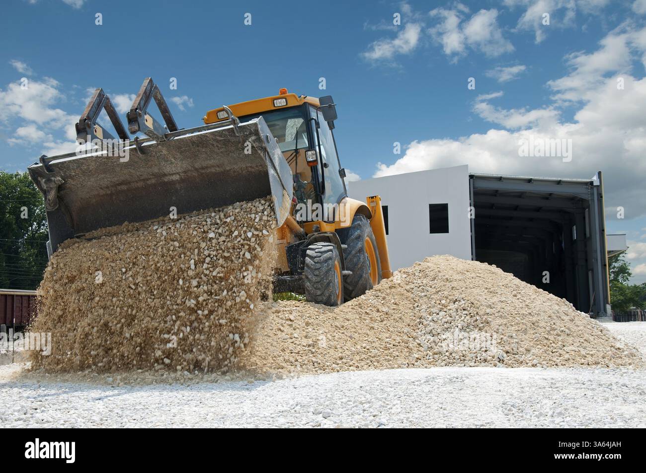 Gelbe Bagger entladen Kies Stockfoto