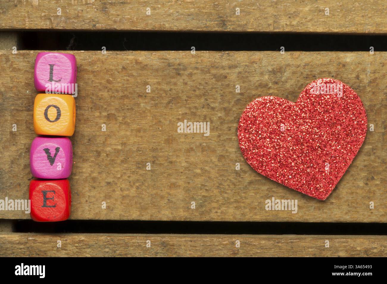 Wortliebe auf bunten Holzwürfeln auf hölzernem Hintergrund und Herz Stockfoto