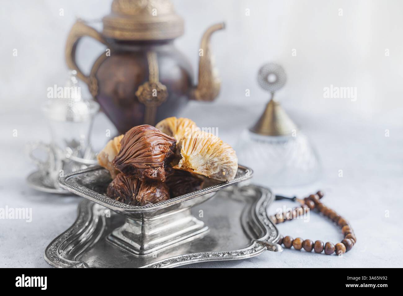 Baklava. Traditionelle süße Speisen aus dem Nahen Osten, serviert mit einer kunstvollen Teekanne in elegantem Ambiente. Stockfoto
