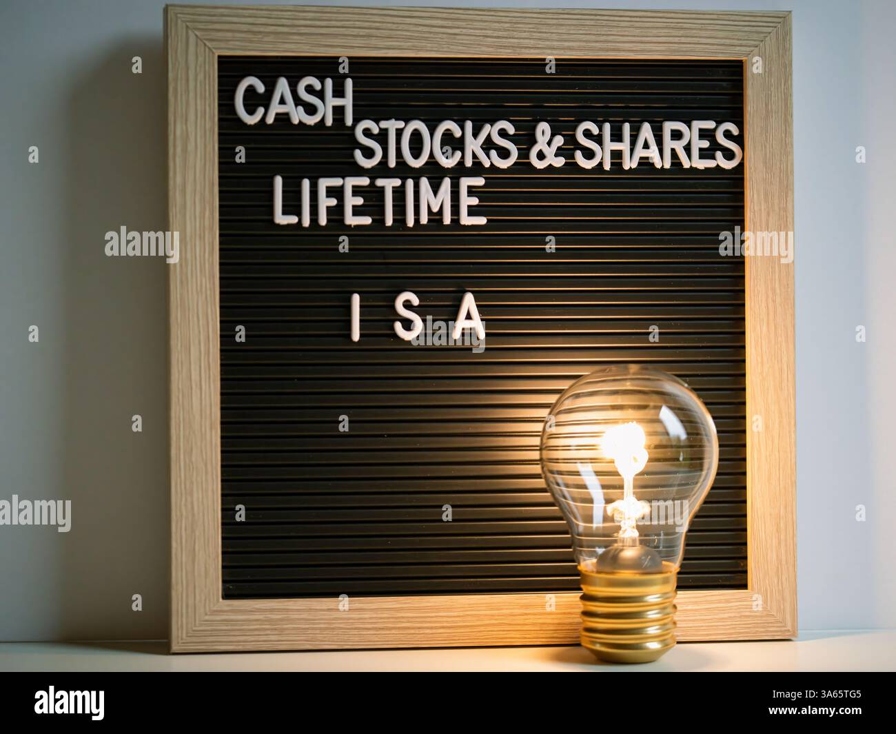 Ein hölzerner Rahmen mit Buchstaben Cash Stock und teilt lebenslange ISAs mit einer Stunde Glaszeit und Investition Stockfoto