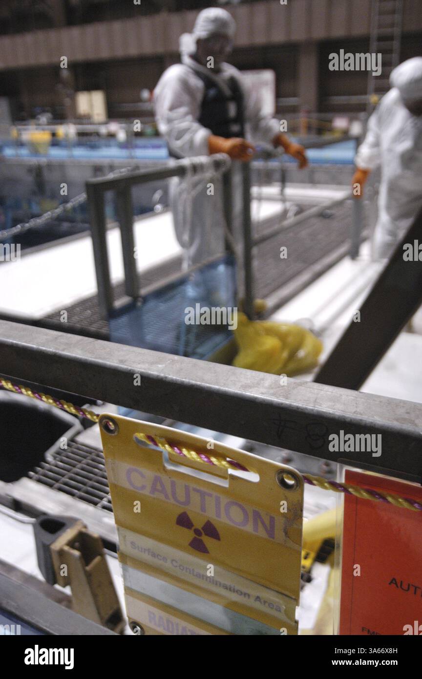 Mai 2004; Avila Beach, CA, USA; ! Ein Strahlenwarnschild hängt am Hochstrahlungsrand, während Arbeiter in Schutzkleidung sich auf Wartungsarbeiten an einem der 440.000-Gallonen-Becken vorbereiten, in denen sich die abgebrannten Brennelemente des Kernreaktors befinden. Kritiker argumentieren, dass die abgebrannten Brennelemente ein ideales Ziel für Terroristen sind, die einen Angriff nutzen könnten, um das Becken zu entwässern und die abgebrannten Brennelemente zu entzünden, was zu einer langfristigen radioaktiven Kontamination der kalifornischen Zentralküste führt. Die Anlagenbetreiber sagen, dass die Tiefe der Pools zusammen mit der Stahl- und Betonauskleidung des Pools dafür verantwortlich ist Stockfoto