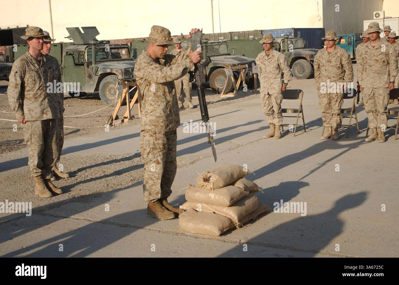 25. August 2004; Mahmudiyah, Irak; Ein Marine mit Kompanie E, 2. Bataillon, 2. Marine-Regiment, bereitet sich darauf vor, während einer Gedenkfeier am 25. August ein Gewehr in Sandsäcke zu setzen. Die Zeremonie war für CPL Christopher W. Belchik, einen Truppenführer der Firma. Er starb am 22. August an Schrapnell-Wunden. Stockfoto