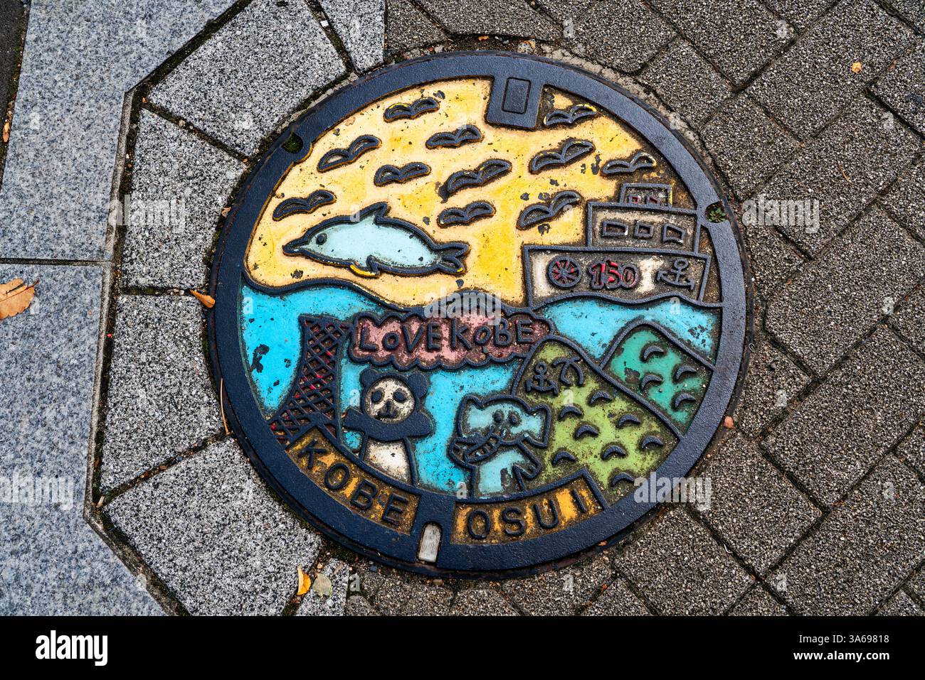 Illustrierte Mannloch-Abdeckung in Kobe, Japan, mit lokalen Sehenswürdigkeiten. Stockfoto