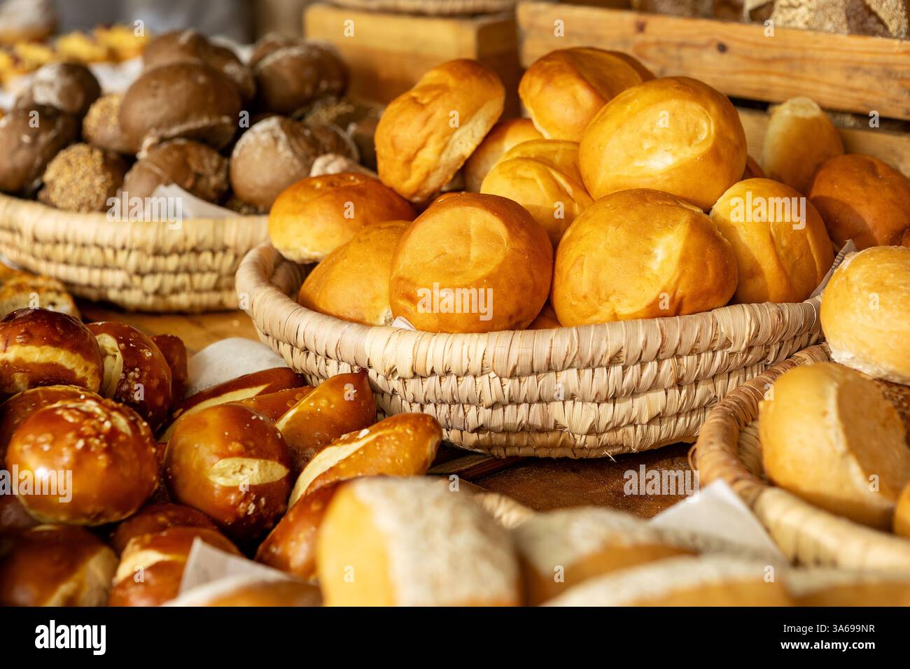 Das luxuriöse Hotelfrühstück umfasst frisch gebackene Brötchen, handwerkliches Gebäck und Brezeln in rustikalen Korbkörben. Stockfoto
