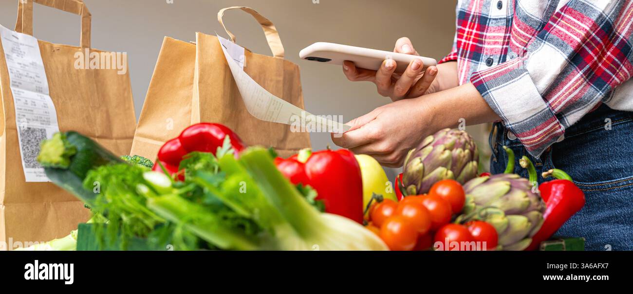 Frisches Gemüse auf verschwommenem Hintergrund einer Person, die den QR-Code des Barbelegs scannt Stockfoto