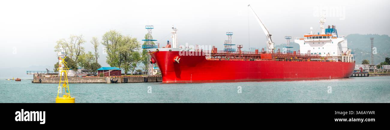 Roter Öltanker, der im Industriehafen verankert ist und für Seeschifffahrtslogistik, Energieexport, Rohöltransport, internationalen Handel und globale Frachttransportindustrie verwendet wird Stockfoto