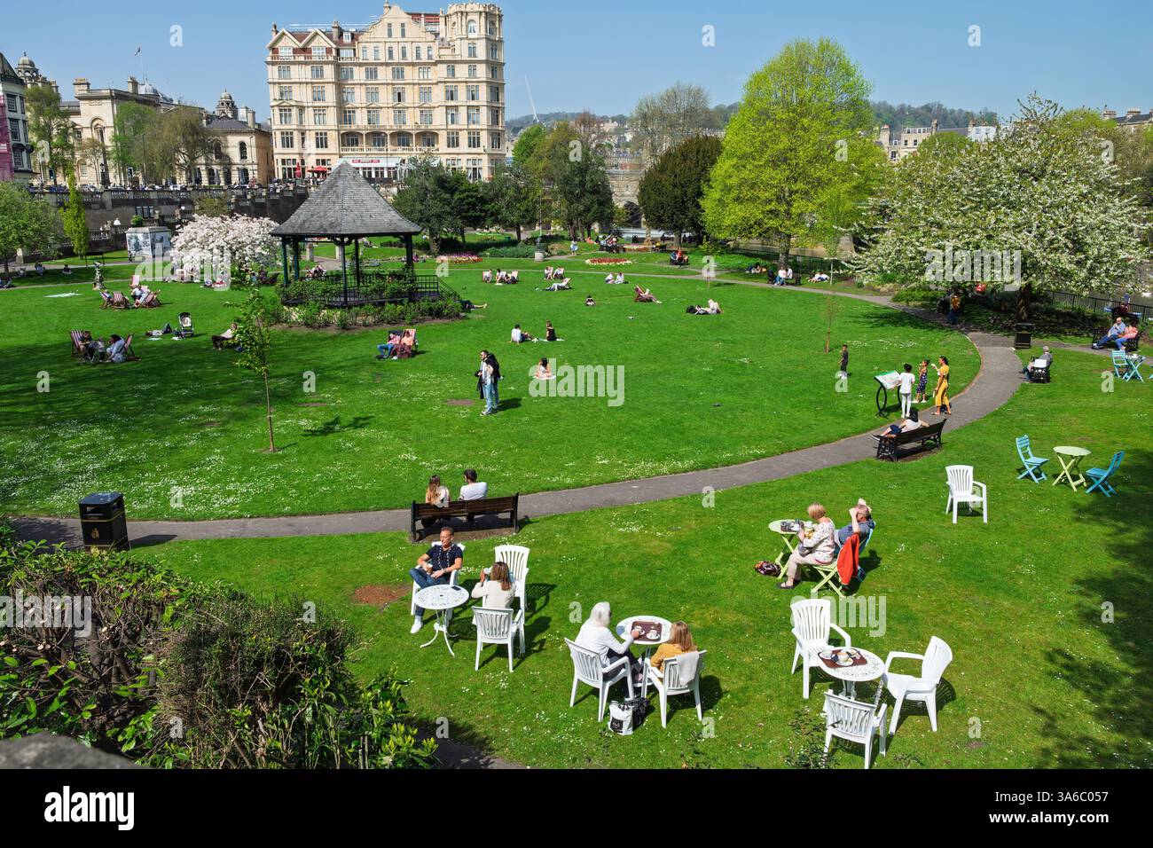 Leute, die warmes Wetter genießen, sitzen in Parade Gardens, Bath, Großbritannien. Der Park ist eine beliebte Touristenattraktion, ein Wahrzeichen neben dem Fluss Avon Stockfoto