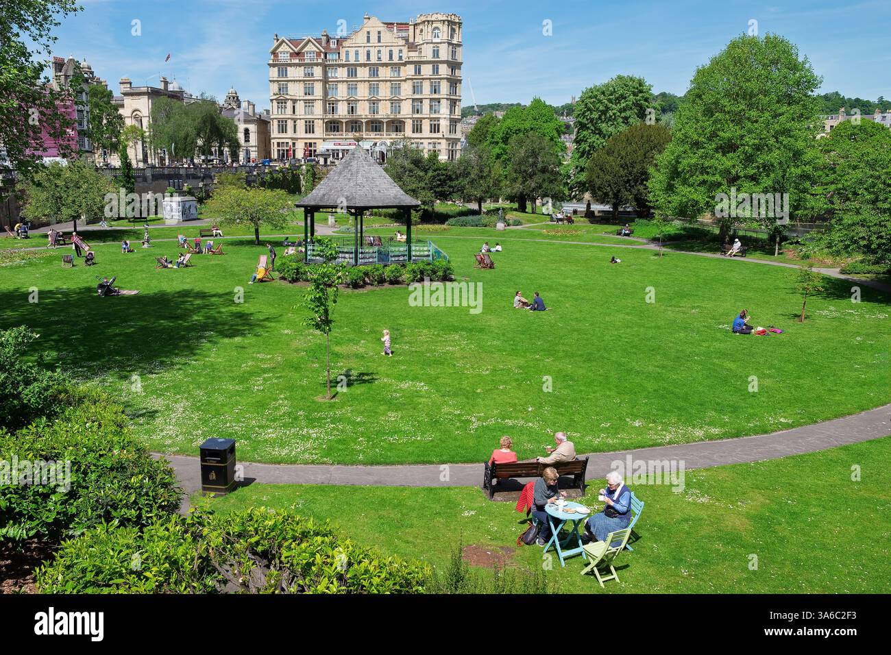 Leute, die warmes Wetter genießen, sitzen in Parade Gardens, Bath, Großbritannien. Der Park ist eine beliebte Touristenattraktion, ein Wahrzeichen neben dem Fluss Avon Stockfoto