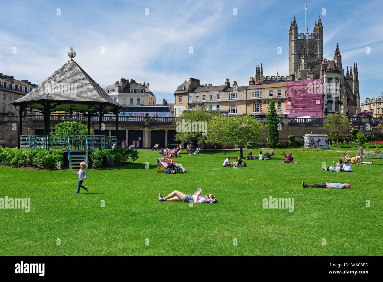 Leute, die warmes Wetter genießen, sitzen in Parade Gardens, Bath, Großbritannien. Der Park ist eine beliebte Touristenattraktion, ein Wahrzeichen neben dem Fluss Avon Stockfoto