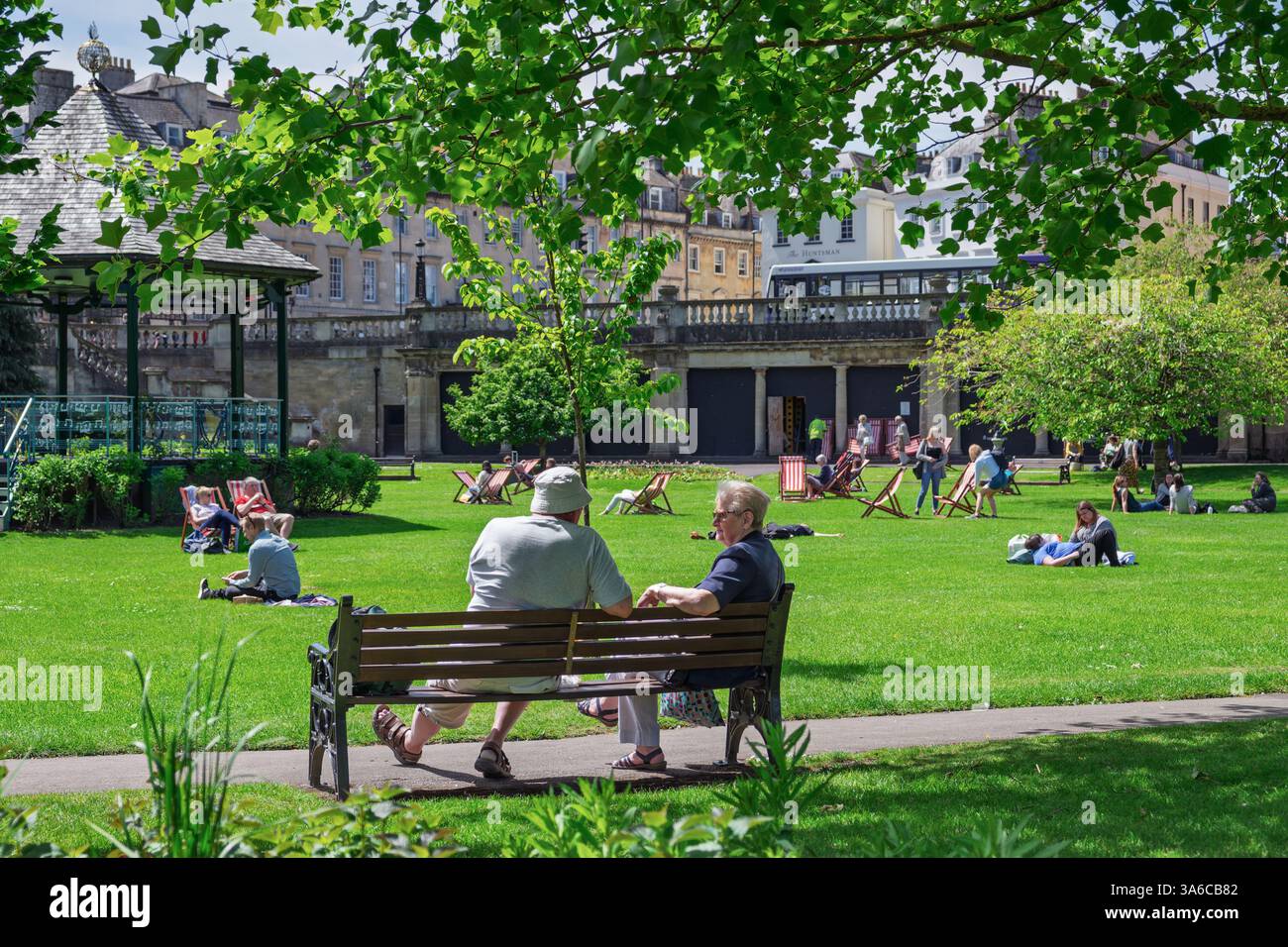 Leute, die warmes Wetter genießen, sitzen in Parade Gardens, Bath, Großbritannien. Der Park ist eine beliebte Touristenattraktion, ein Wahrzeichen neben dem Fluss Avon Stockfoto