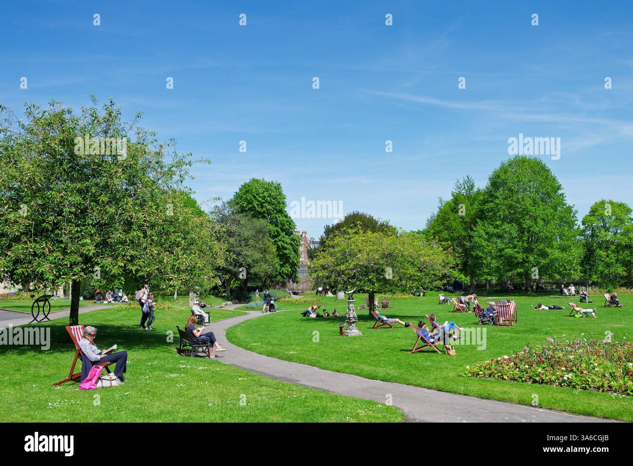 Leute, die warmes Wetter genießen, sitzen in Parade Gardens, Bath, Großbritannien. Der Park ist eine beliebte Touristenattraktion, ein Wahrzeichen neben dem Fluss Avon Stockfoto