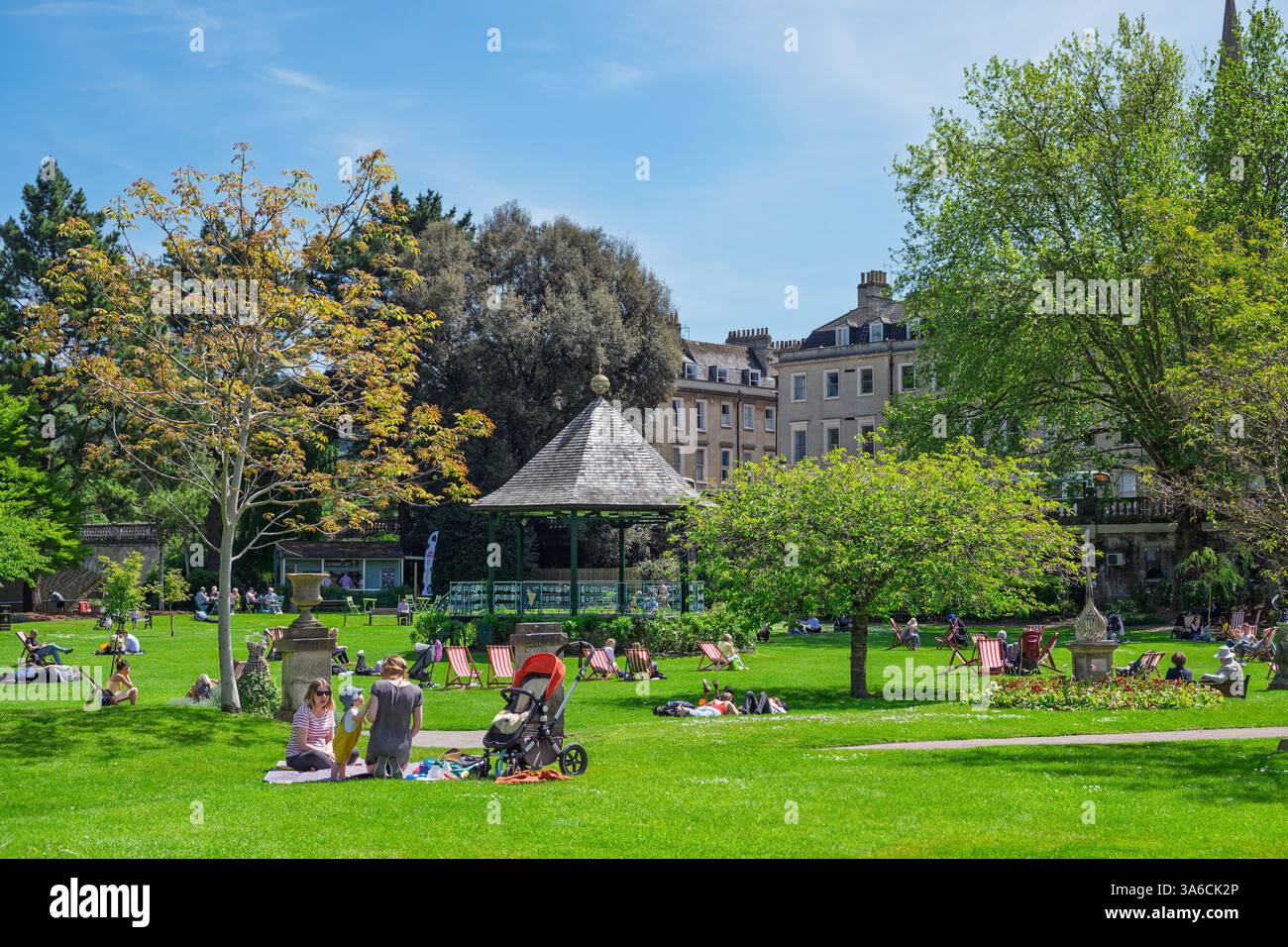 Leute, die warmes Wetter genießen, sitzen in Parade Gardens, Bath, Großbritannien. Der Park ist eine beliebte Touristenattraktion, ein Wahrzeichen neben dem Fluss Avon Stockfoto