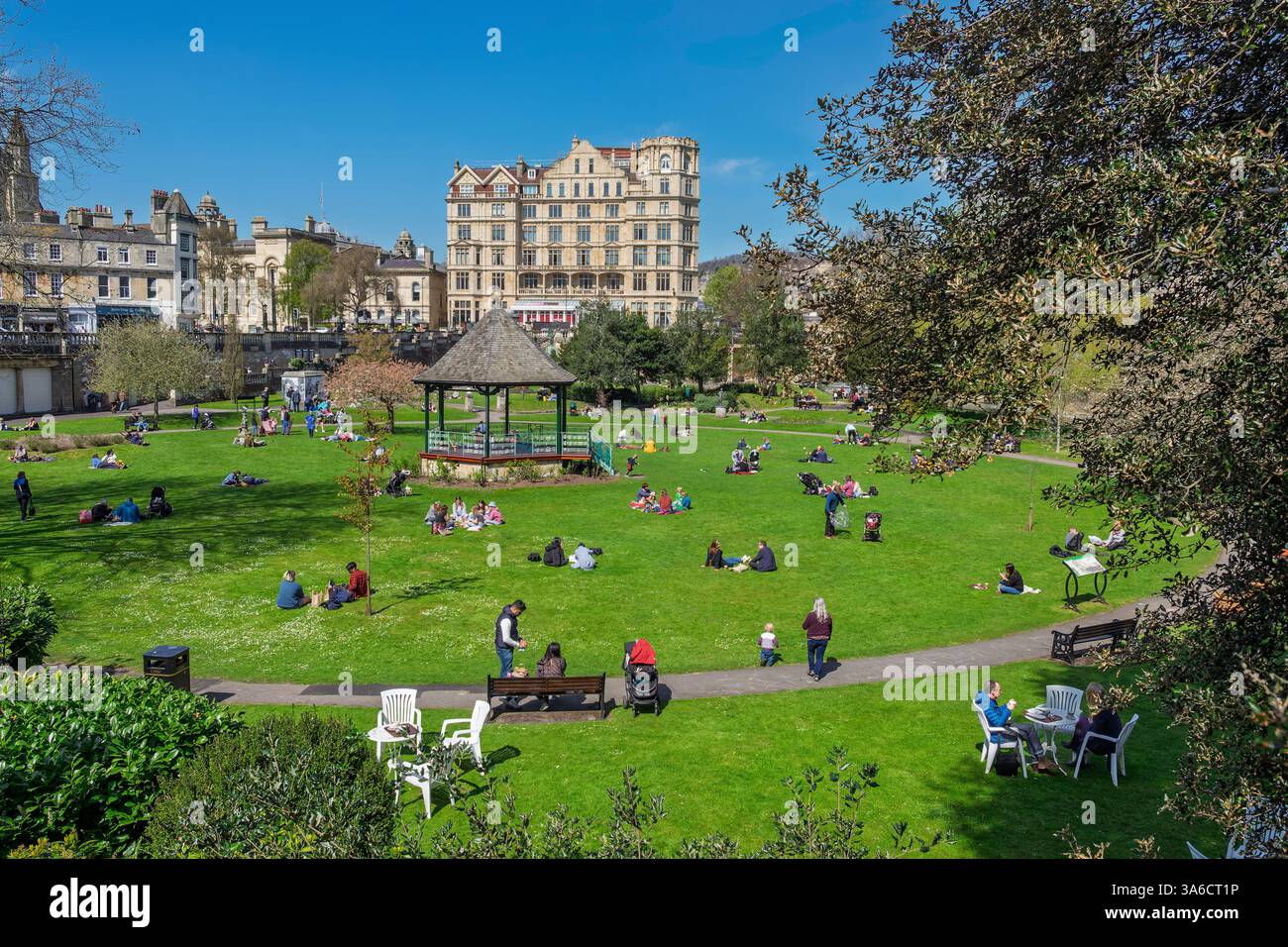 Leute, die warmes Wetter genießen, sitzen in Parade Gardens, Bath, Großbritannien. Der Park ist eine beliebte Touristenattraktion, ein Wahrzeichen neben dem Fluss Avon Stockfoto