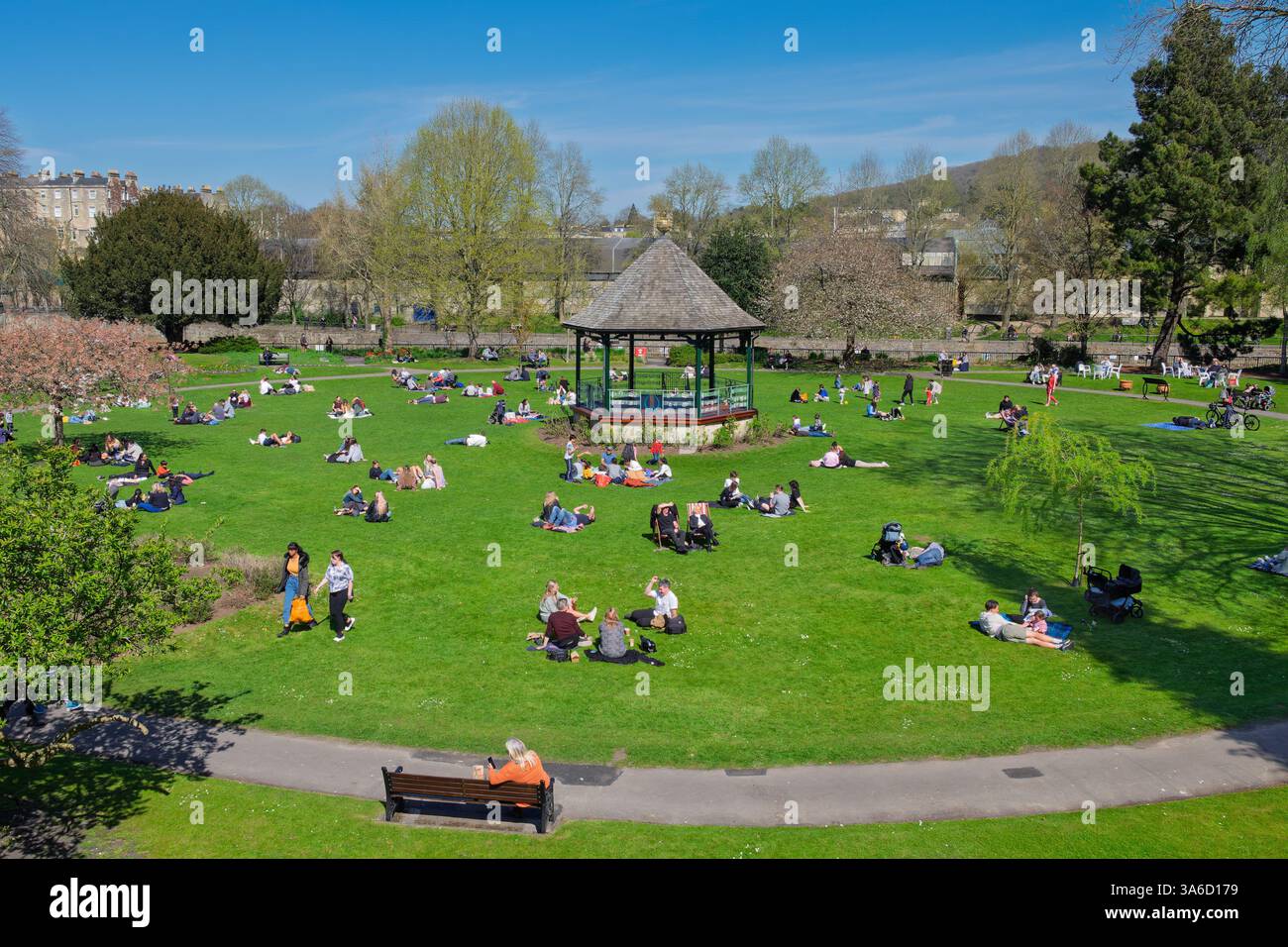 Leute, die warmes Wetter genießen, sitzen in Parade Gardens, Bath, Großbritannien. Der Park ist eine beliebte Touristenattraktion, ein Wahrzeichen neben dem Fluss Avon Stockfoto