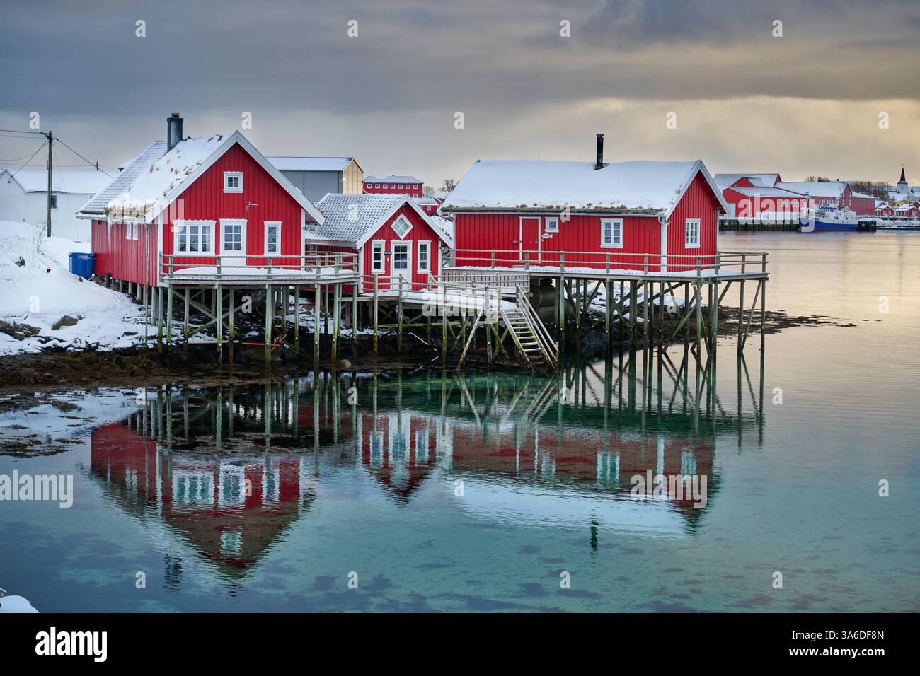 Rote Häuser am Wasser mit Reflexen, Blick auf reine bei Sonnenuntergang, Lofoten, Norwegen, Europa Stockfoto