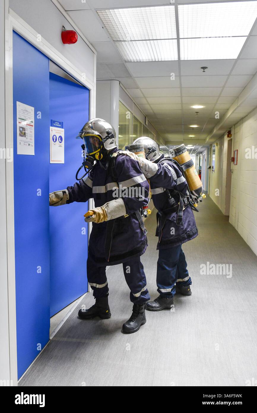 Feuerwehrübungen in einem mechanischen Raum: Zwei Feuerwehrleute in voller Ausrüstung, mit Helm und abgeschlossenem Atemgerät (SCBA) Stockfoto