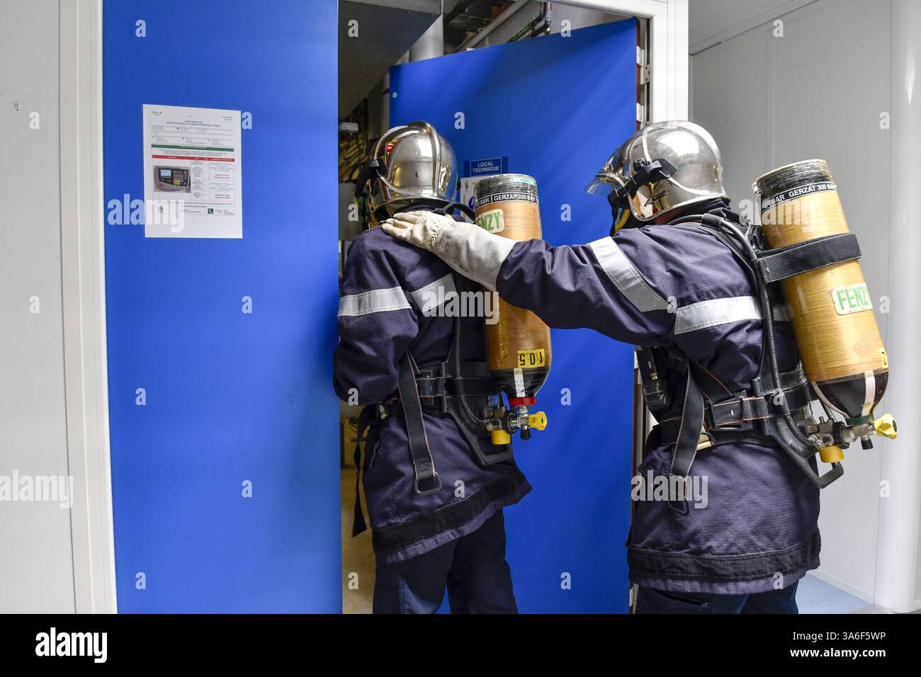 Feuerwehrübungen in einem mechanischen Raum: Zwei Feuerwehrleute in voller Ausrüstung, mit Helm und abgeschlossenem Atemgerät (SCBA) Stockfoto