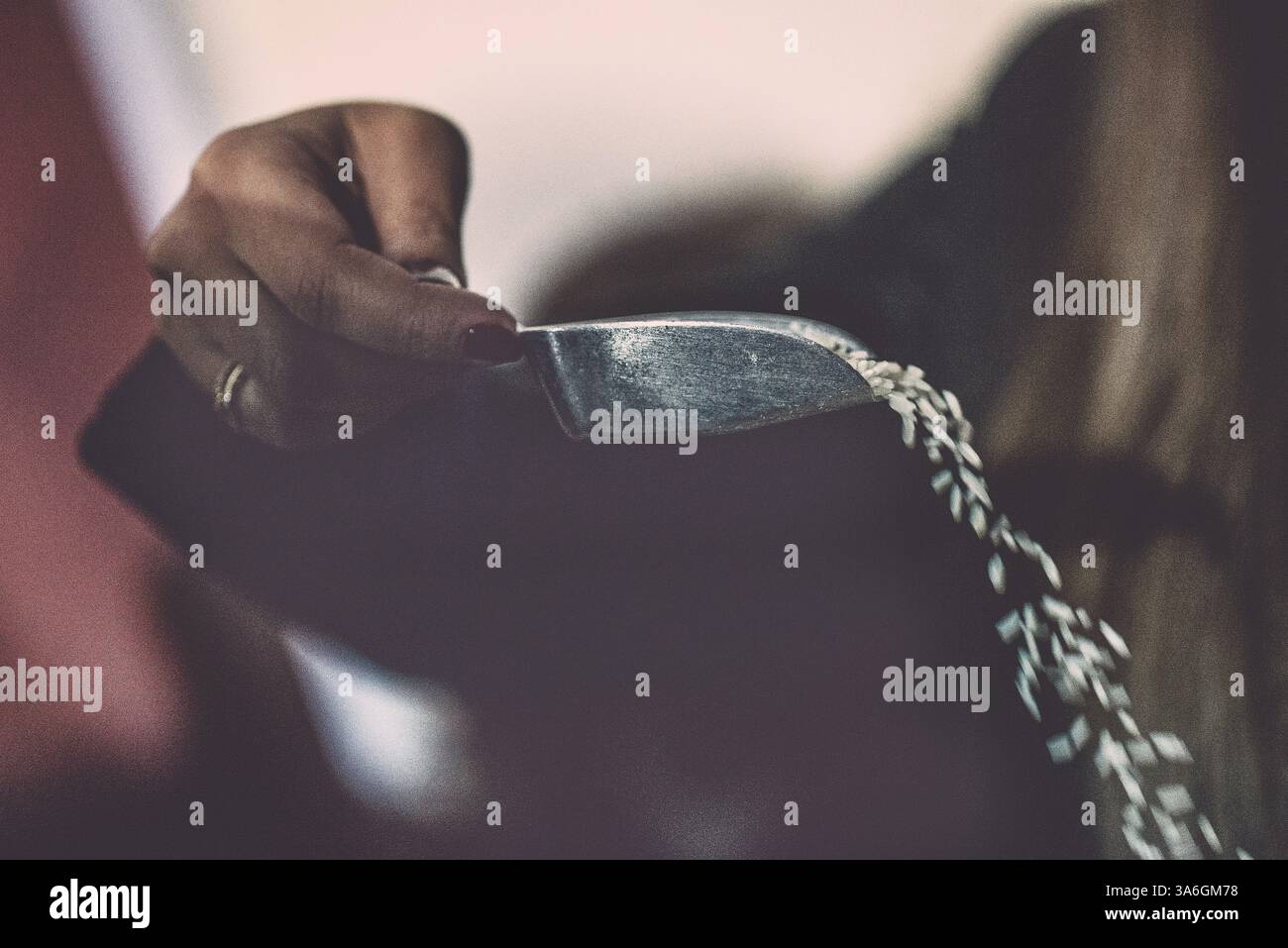 Dem Paar Reis mit einer Schaufel nach dem Ende einer griechischen orthodoxen Hochzeit zuwerfen Stockfoto