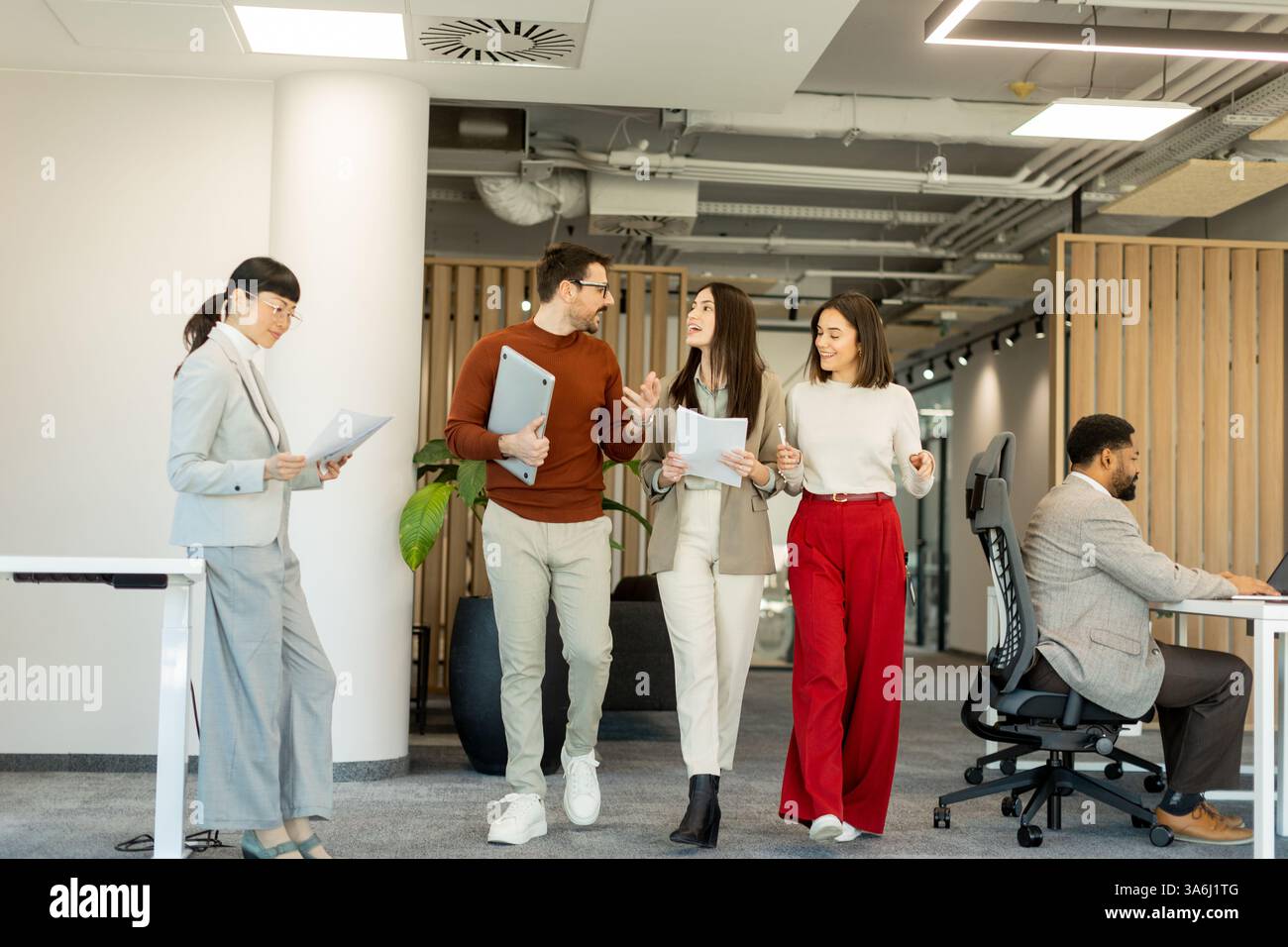 Eine Gruppe von Fachleuten führt lebhafte Diskussionen, während sie Dokumente überprüfen und Teamarbeit und Kreativität in einem hellen, modernen Arbeitsbereich verkörpern Stockfoto