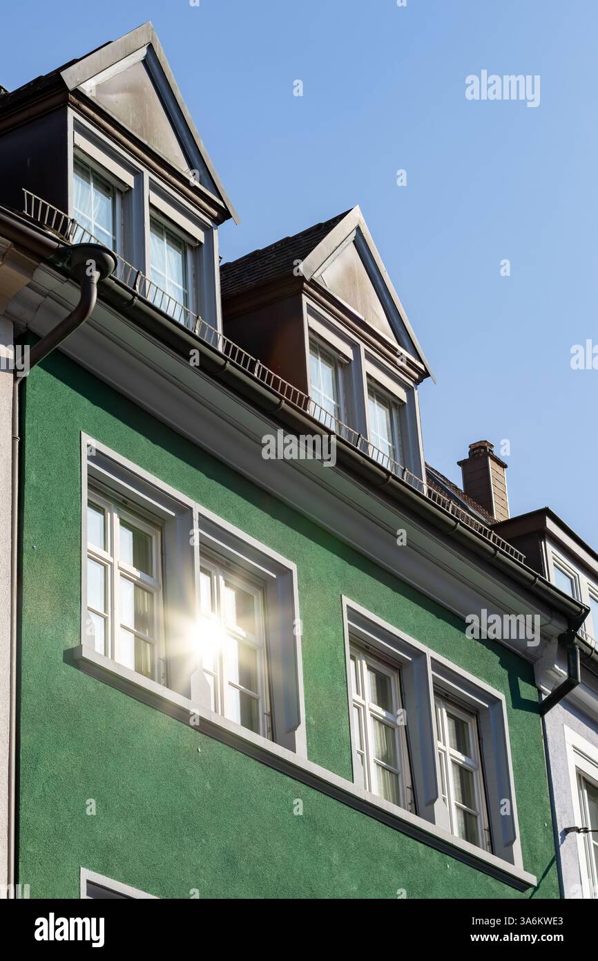 Die Sonne spiegelt sich im Fenster eines renovierten alten Gebäudes Stockfoto