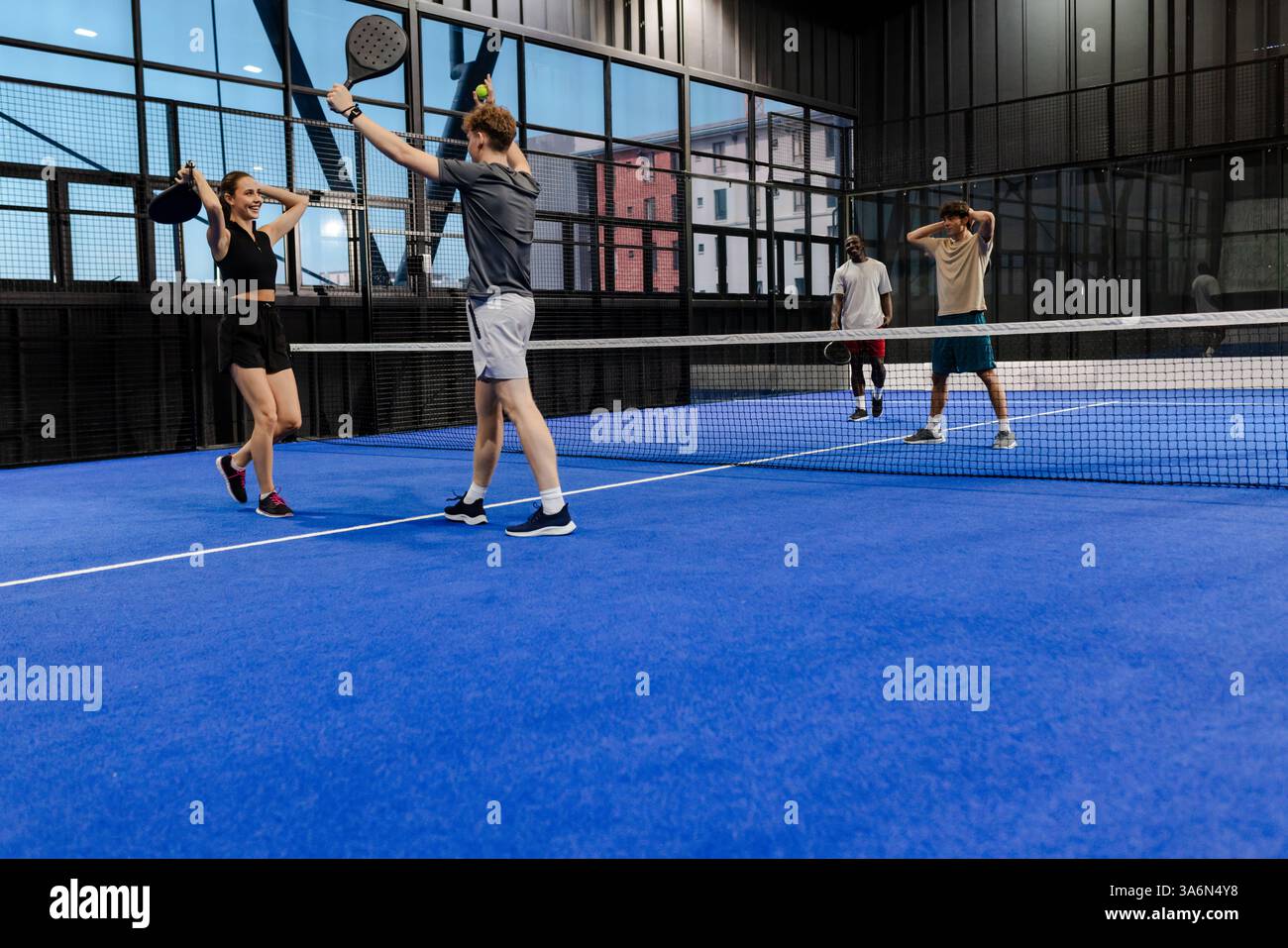 Freunde spielen Padel-Tennis im Haus, feiern den Sieg mit hoher Energie, Kopierraum Stockfoto