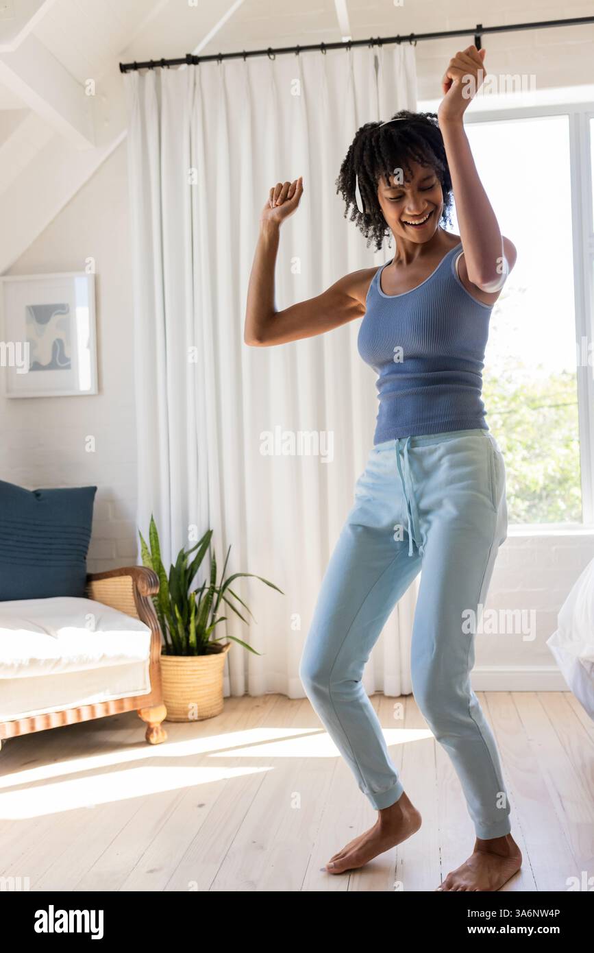 Fröhliche Frau tanzt barfuß im hellen Wohnzimmer, genießt unbeschwerte Momente, Kopierraum Stockfoto