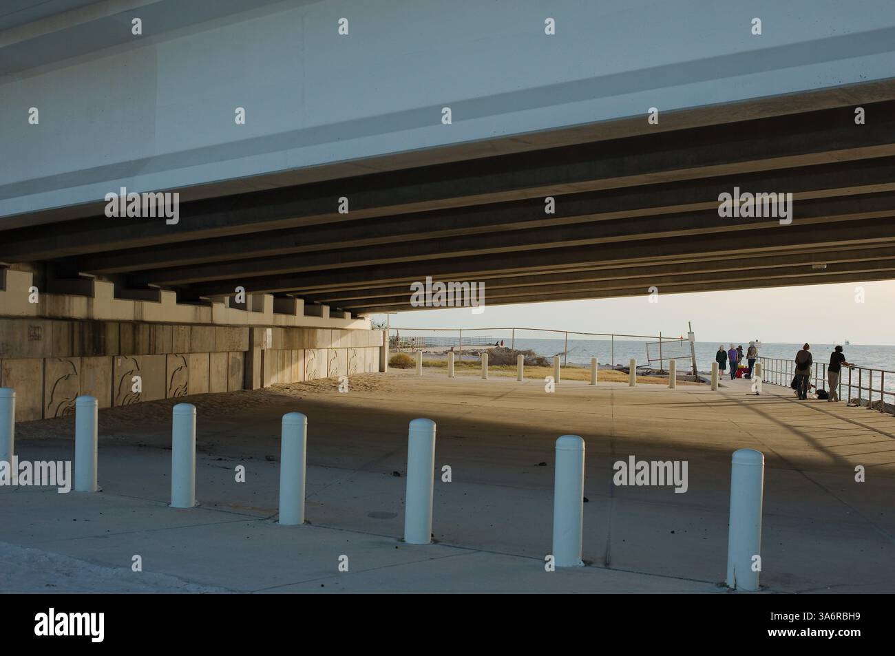 Eine Gruppe von Menschen fischt mit Ruten unter einer Zugbrücke am John's Pass zwischen Treasure Island und Maderia Beach Florida. Große Felsen. Brücke im oberen p Stockfoto