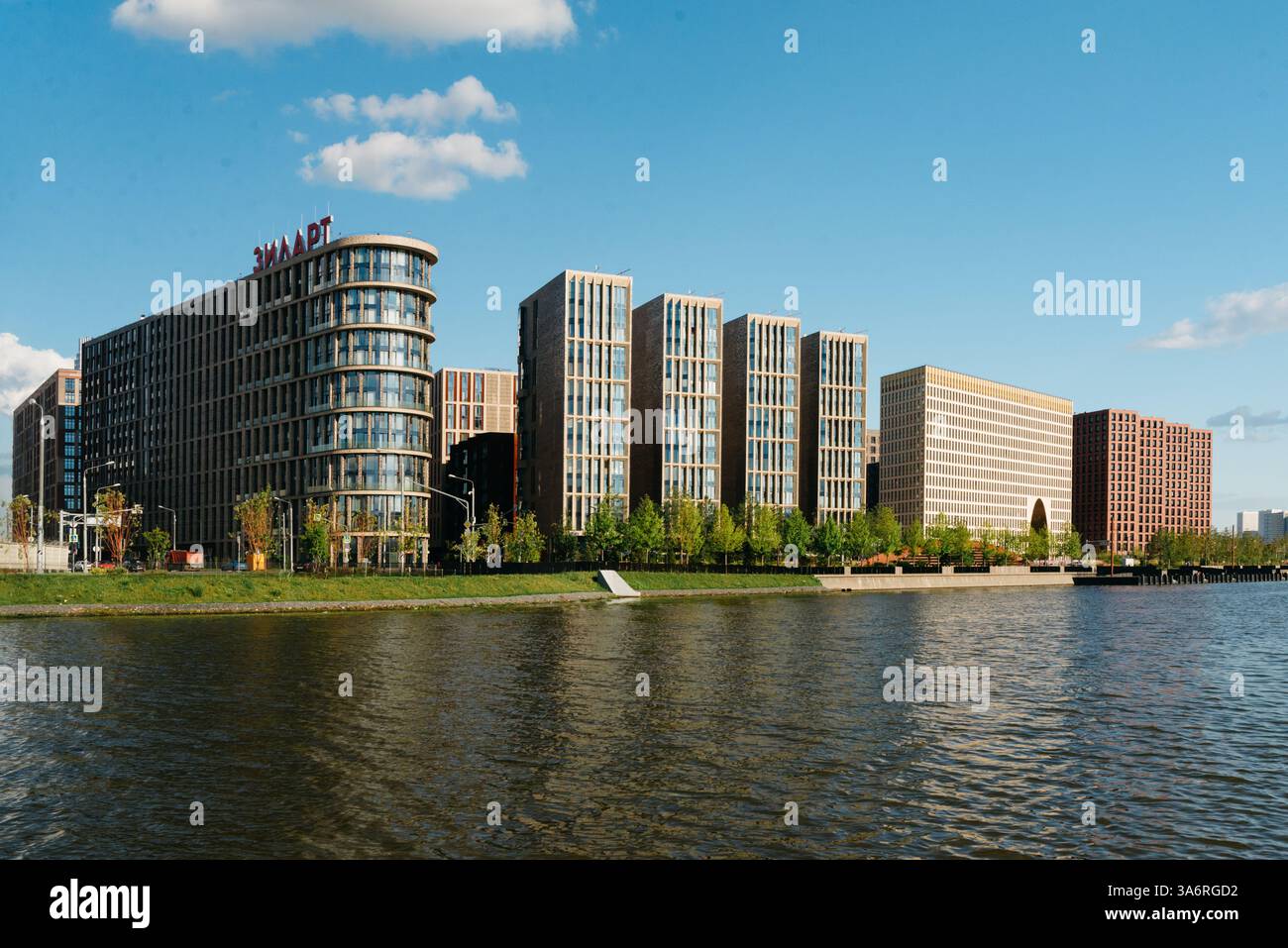 Moskau Russland - Juli 30 2023 - Eine Reihe zeitgenössischer Gebäude mit Glasfassaden und eleganter Architektur säumt das Ufer unter einem klaren blauen Himmel Stockfoto