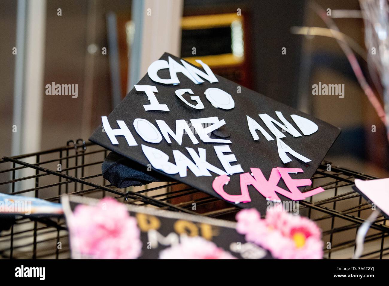 Die verzierte Mortarboard eines Highschool-Seniors mit der Aufschrift „kann ich nach Hause gehen und einen Kuchen backen“ wird während einer Abschlussfeier der Highschool gesehen. Stockfoto