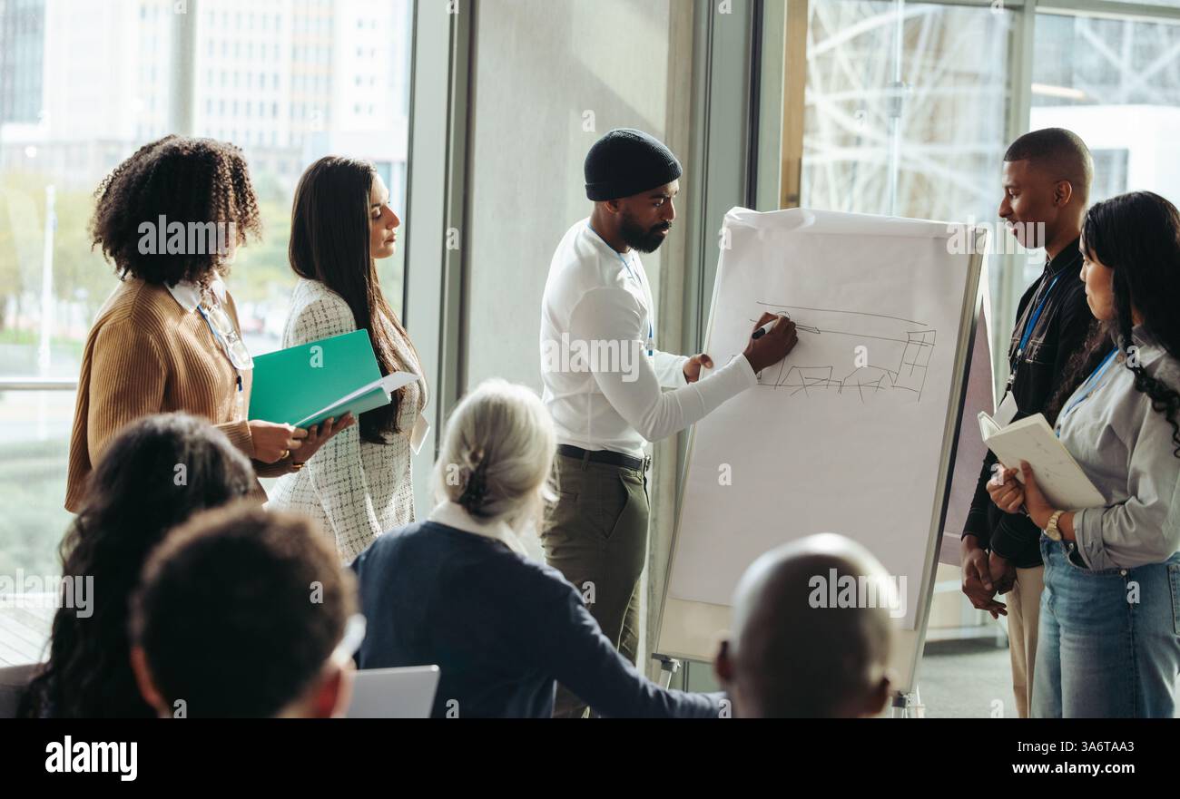 Kollegen, die während eines geschäftlichen Meetings in einem Unternehmen Teamarbeit leisten und kreative Ideen und Strategien in einem modernen Büroumfeld diskutieren, mit verschiedenen Themen Stockfoto