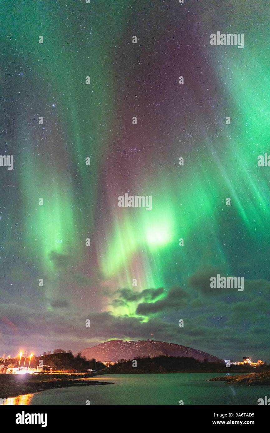 Wunderschöne Aurora Borealis über dem Haus auf der Insel Kvaløya, tanzende Nordlichter mit grünem Licht, roten und lila Strikes, klare farbige Strahlen Stockfoto