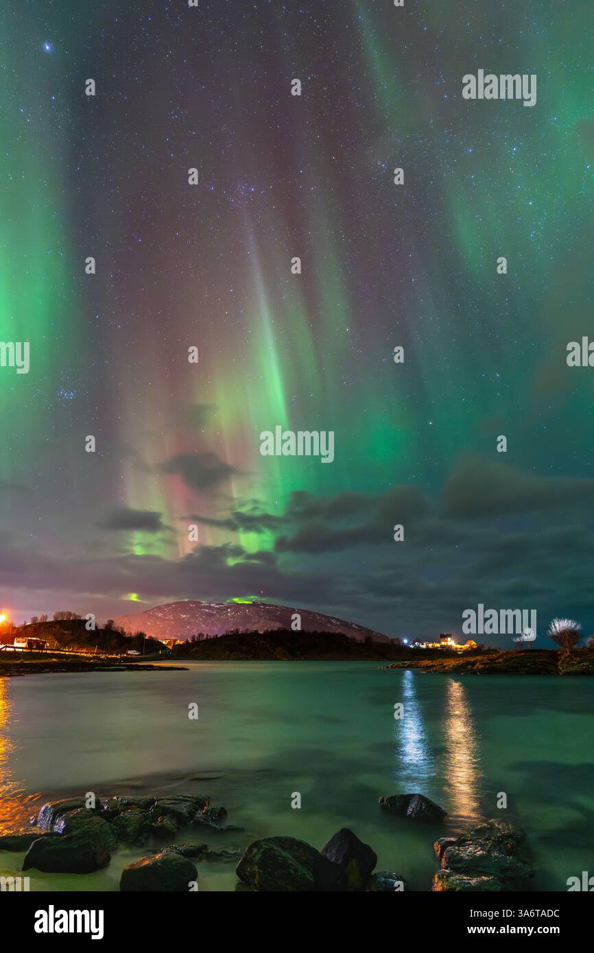 Wunderschöne Aurora Borealis über dem Haus auf der Insel Kvaløya, tanzende Nordlichter mit grünem Licht, roten und lila Strikes, klare farbige Strahlen Stockfoto
