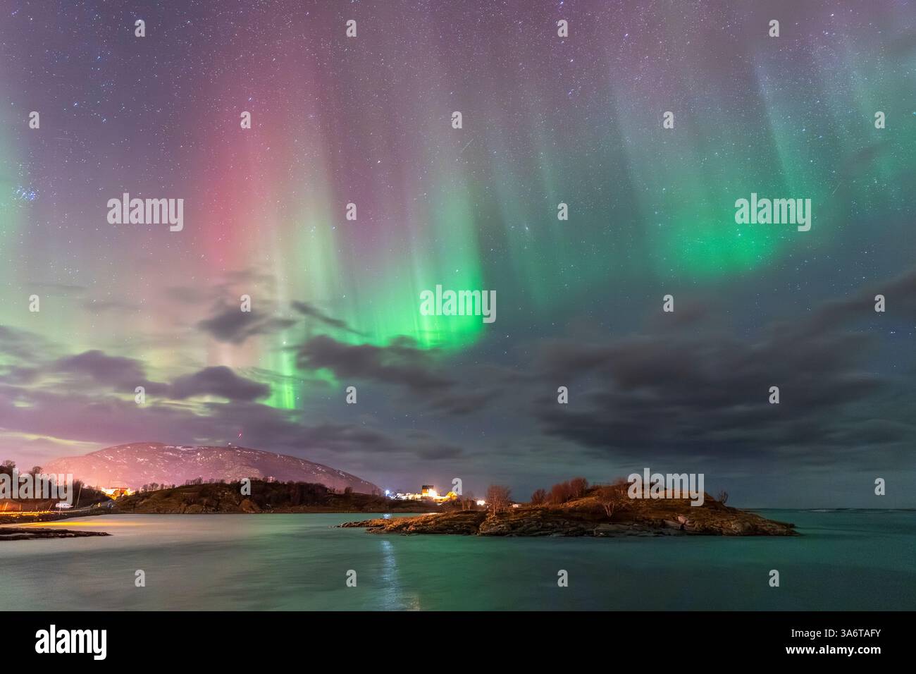 Wunderschöne Aurora Borealis über dem Haus auf der Insel Kvaløya, tanzende Nordlichter mit grünem Licht, roten und lila Strikes, klare farbige Strahlen Stockfoto