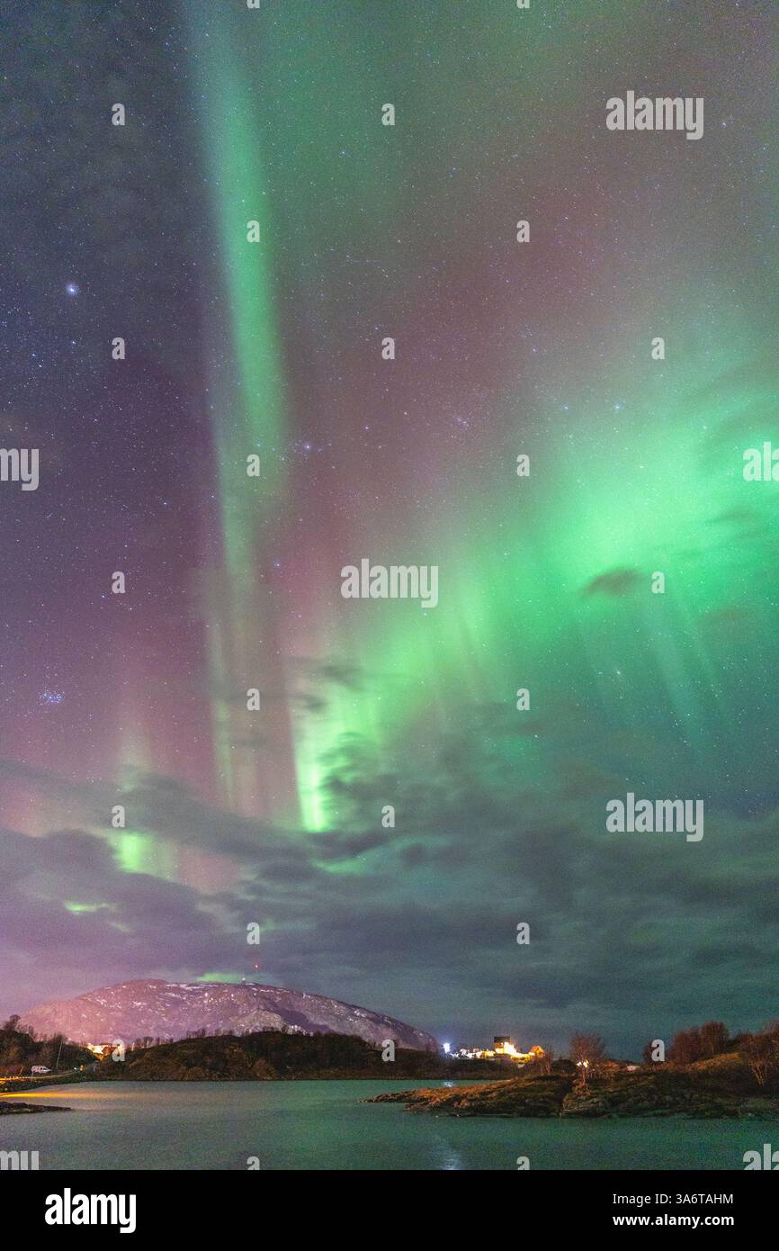 Wunderschöne Aurora Borealis über dem Haus auf der Insel Kvaløya, tanzende Nordlichter mit grünem Licht, roten und lila Strikes, klare farbige Strahlen Stockfoto