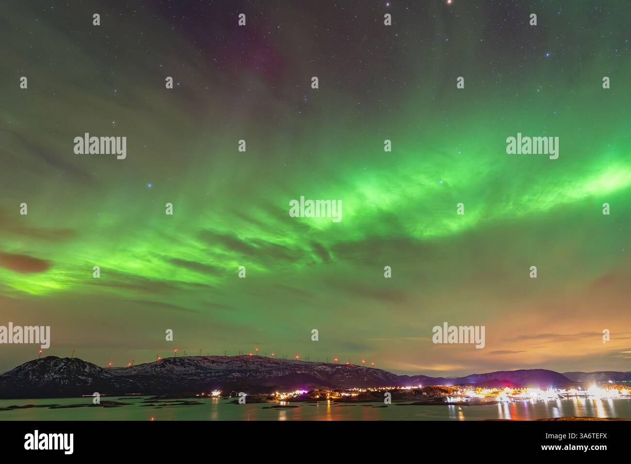 Wunderschöne Aurora Borealis über dem Haus auf der Insel Kvaløya, tanzende Nordlichter mit grünem Licht, roten und lila Strikes, klare farbige Strahlen Stockfoto